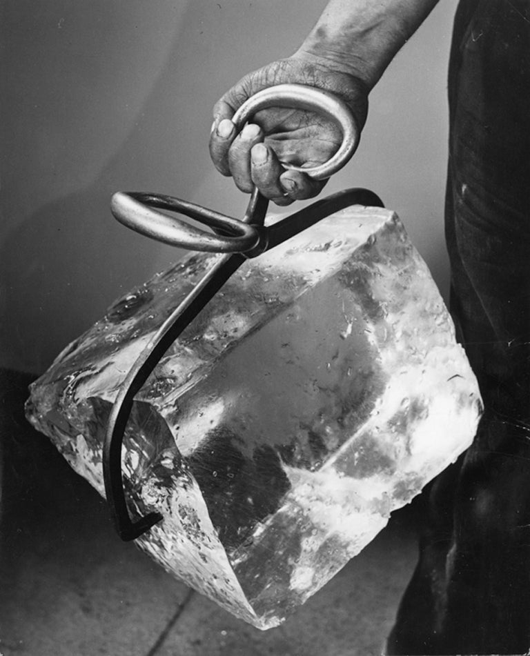 Nina Leen Black and White Photograph - Man Holding Block of Ice