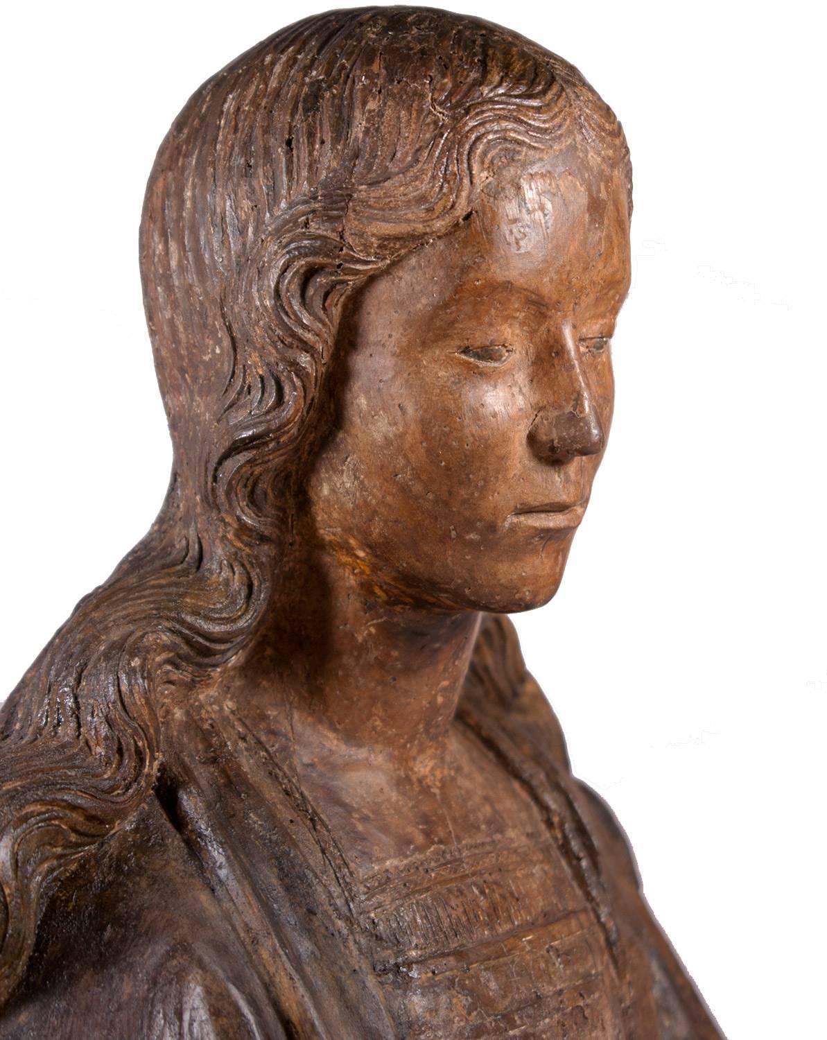 This beautiful bust of a woman dates back to the junction of the late Gothic and the Renaissance. From the late Gothic, it receives the beautiful pictorial effect of curly hairs, and the realism of the face ; from the Renaissance, the classical