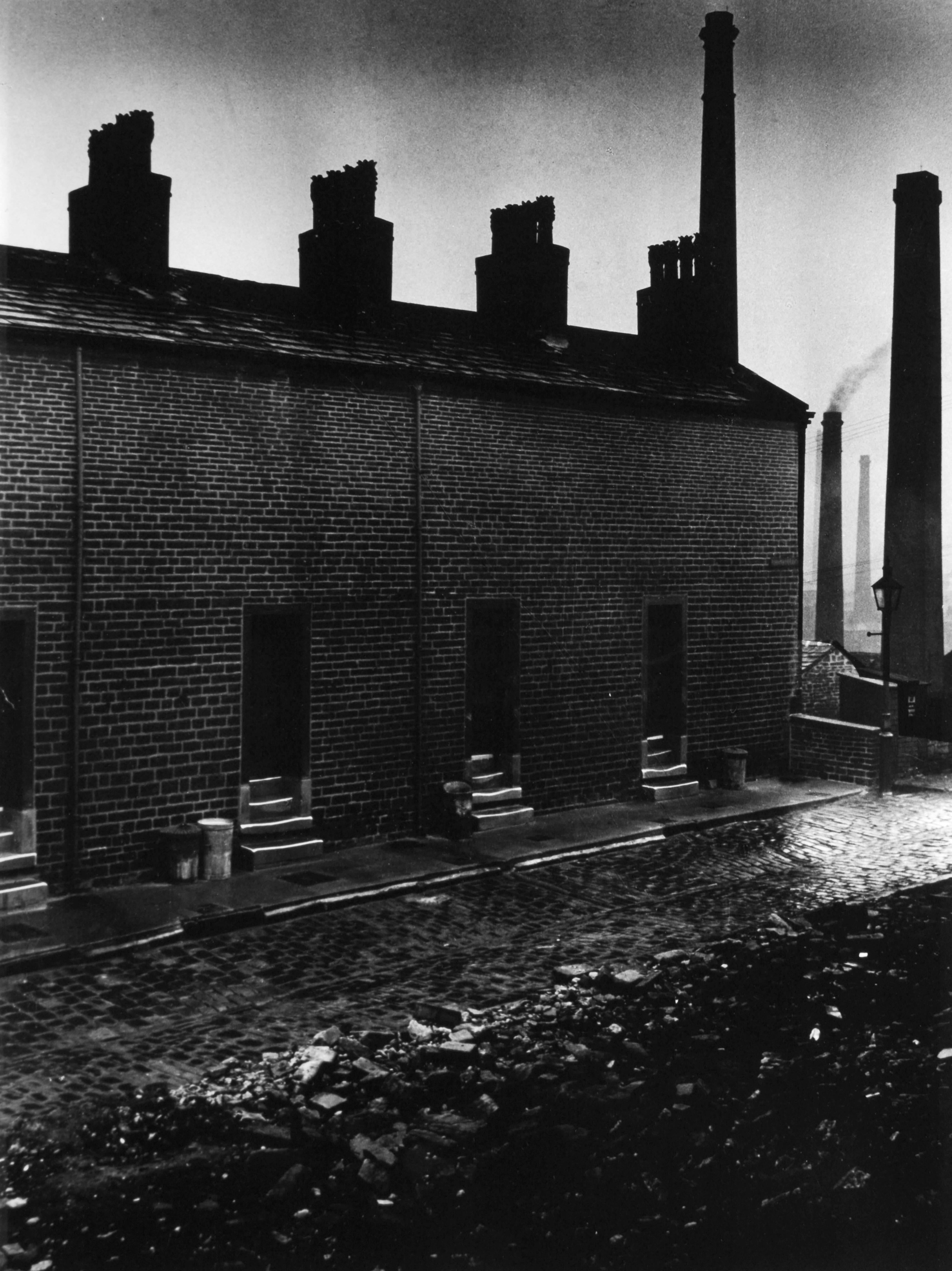 Häuser der Bergleute ohne Fenster zur Straße - Bill Brandt
Beschriftet mit "Halifax" und rückseitig mit dem Tintenstempel von Bill Brandt versehen.
Silbergelatineabzug, gedruckt um 1960
9 x 7 3/4 Zoll

Bill Brandt (1904-1983) war einer der Meister