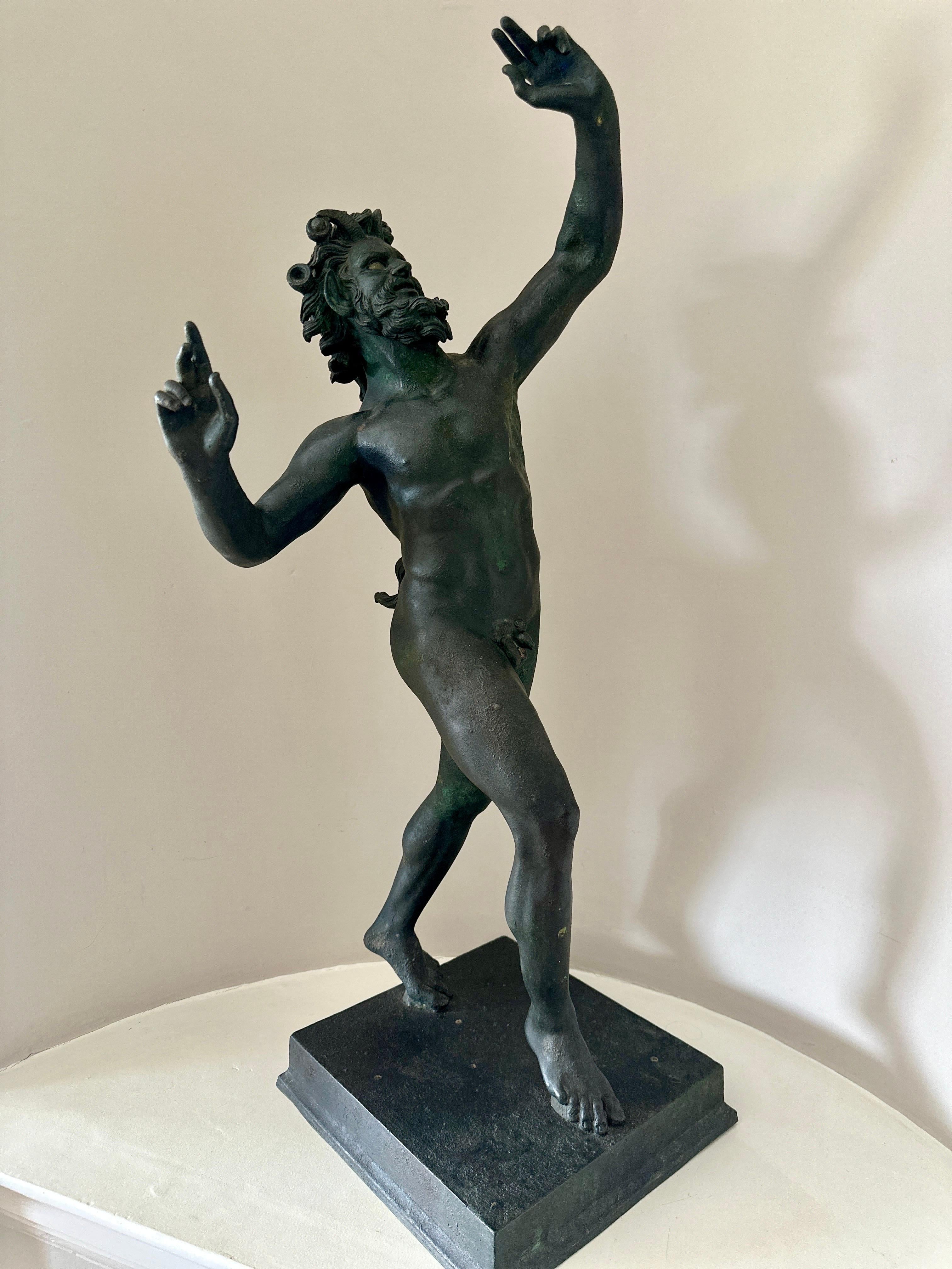 A 19th century 'Grand Tour'  bronze figure of the Dancing Faun, standing on a bronze square plinth. The faun balances on his toes and pivots, his horned head raised, his hair wreathed with acorns. He is smiling lasciviously, flipping his tail, and