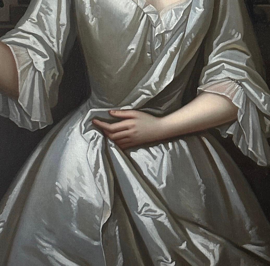 Retrato de Henrietta Paulet, duquesa de Bolton, de soltera Crofts (c. 1682-1730), de tres cuartos, de pie en una terraza con columnas, vestida con un traje de seda color marfil y sosteniendo un ramito de azahar, con una casa de campo y un jardín