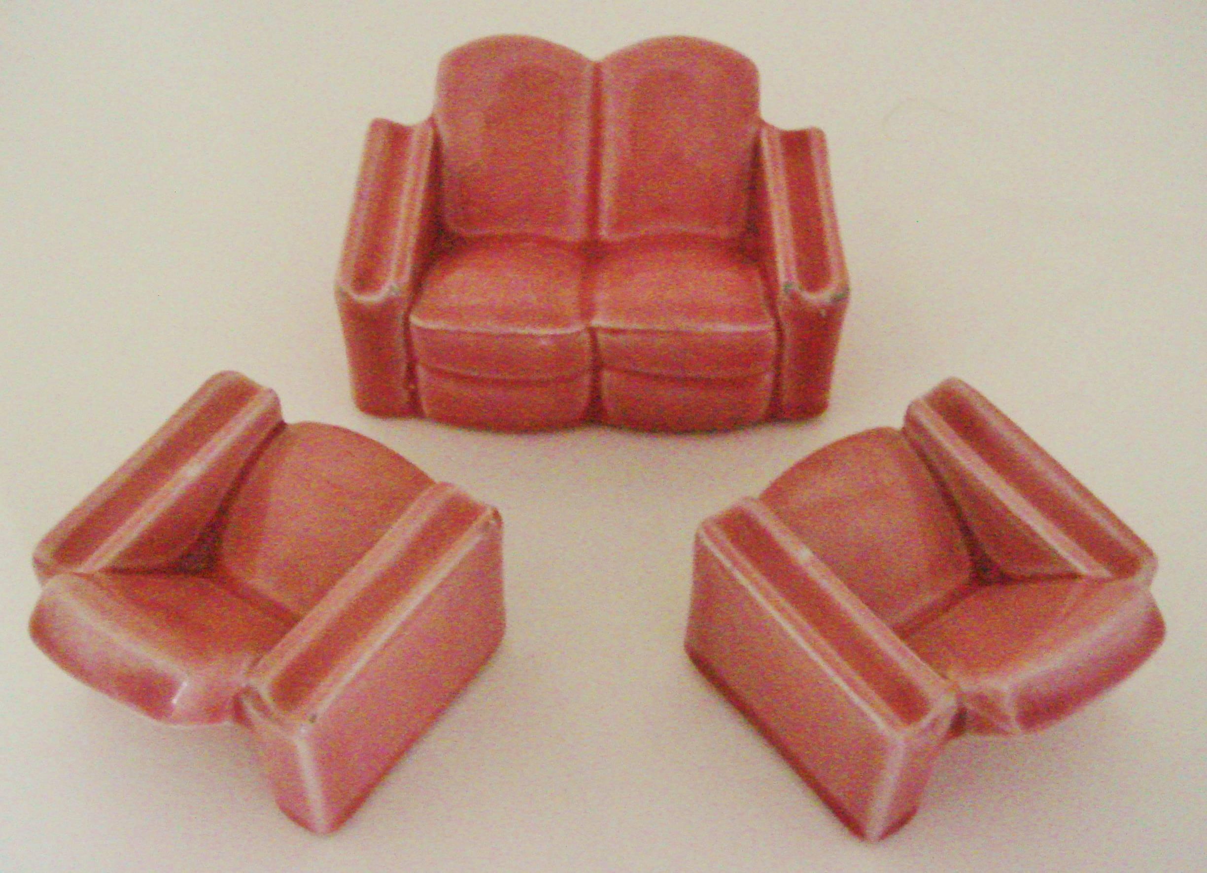 This charming three-piece suite of English Art Deco rose-pink glazed ceramic pieces is comprised of two armchairs (2.75 in deep X 2.25 in high X 2.5 in wide) and a loveseat (2.75 in deep X 2.25 in X 4.0 in wide). They look as though they belong in