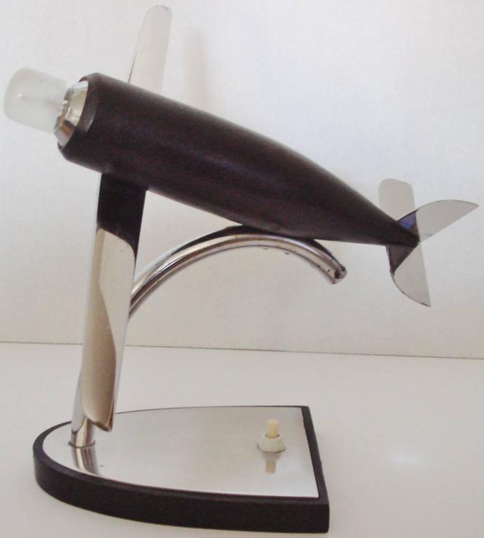 This beautifully designed stylized German Art Deco airplane accent lamp features an ebonized wood fuselage with chrome wings and tail assembly. The engine cowling in chrome is fitted with a light bulb that is operated by a Polish made push-button