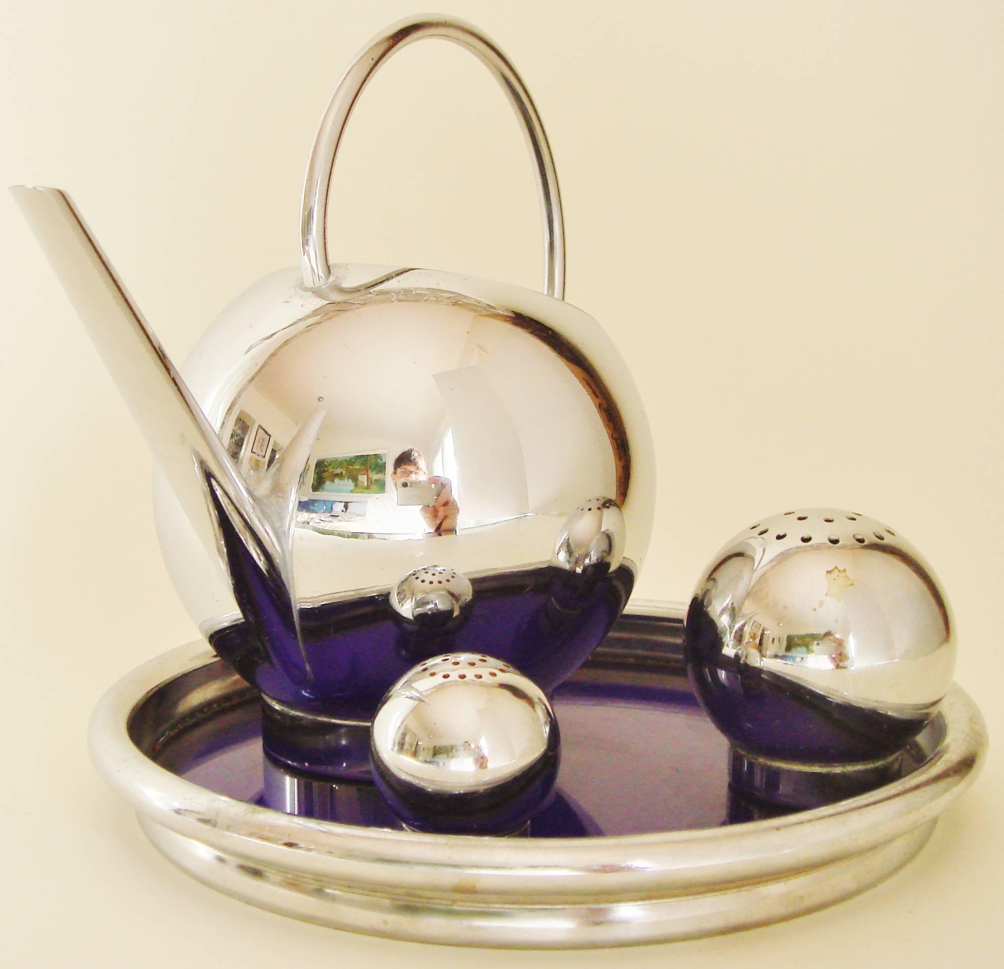 This beautifully designed American Art Deco 4-piece set, with its chrome and cobalt blue glass coaster tray, salt and pepper spheres and maple syrup/melted butter pitcher, was designed for use with either pancakes or corn. Number 28003 in the 1935