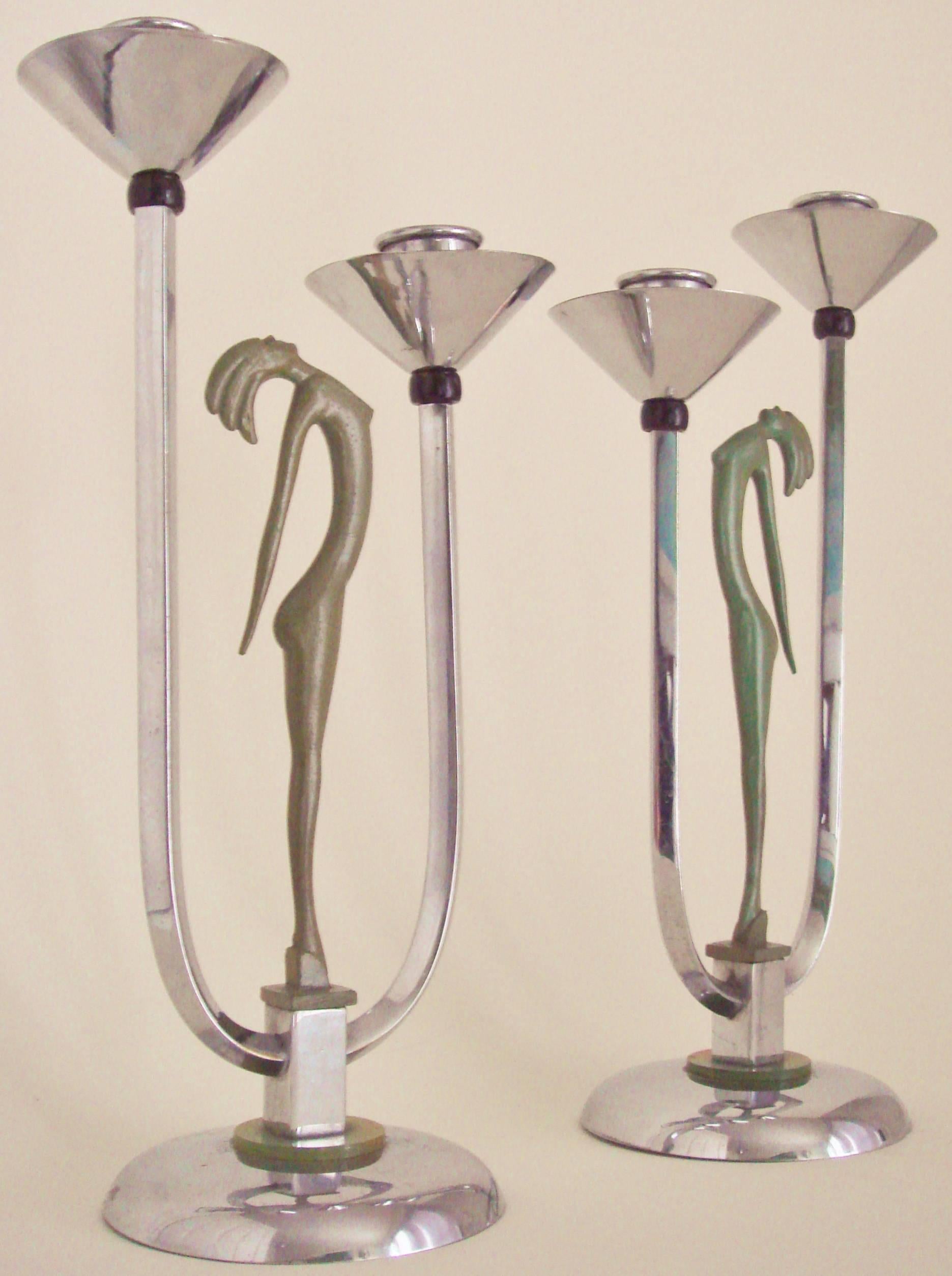 This bold pair of English Art Deco chrome-plated figurative twin candleholders feature moss green enameled stylized female nudes standing in the middle of asymmetrical 
