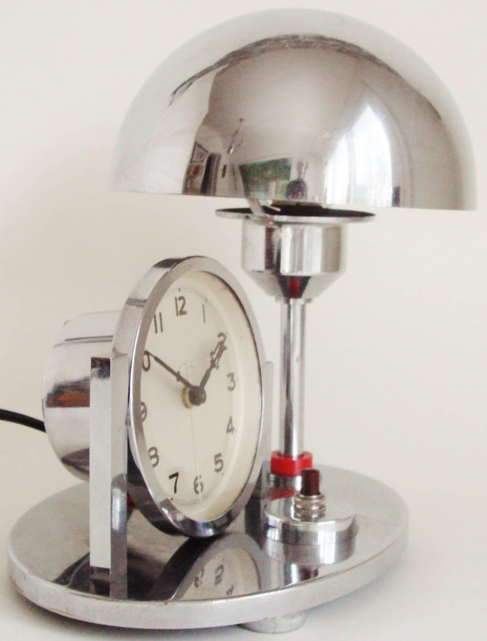 This delightful little German Art Deco chrome combination mechanical alarm clock/reading lamp features an adjustable mushroom shade and red Galalith accents. (Galalith or Erinoid is a European plastic similar to Bakelite). The Bakelite push switch