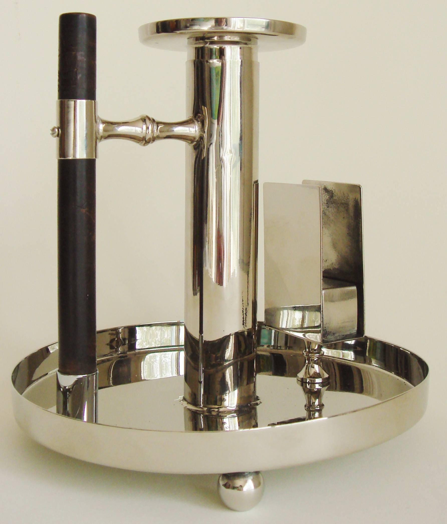 This nickel-plated and ebonized wood German Jugendstil chamber/candlestick was designed by the great Dr. Christopher Dresser and manufactured by the firm of Wurttembergische Metallwarenfabrik/WMF. We have sold an example of this chamberstick before