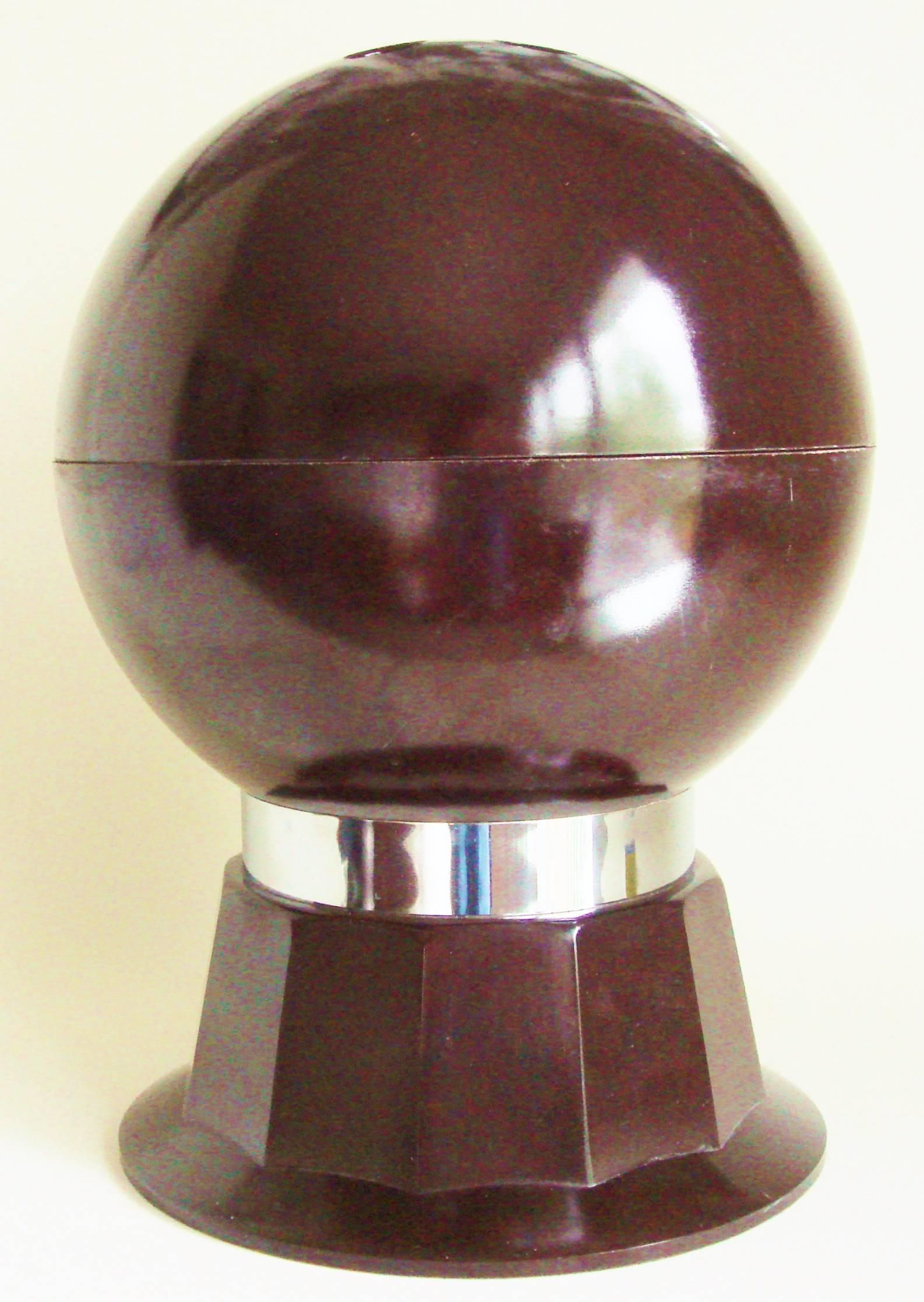 This American Mid-Century brown bakelite and chrome bar set takes the form of a life-size bowling ball standing on a twelve sided fluted plinth that is bound in chrome. When the hemisphere lid of the ball is lifted off, by using the three finger