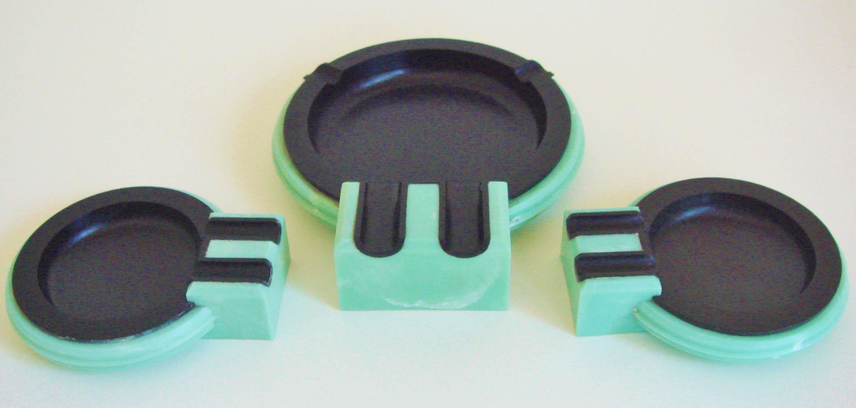 This set of British Art Deco black Bakelite and aqua phenolic ashtrays represent the third version of an iconic design that was originally produced for the launch of the Cunard Liner, RMS Queen Mary. The first or 