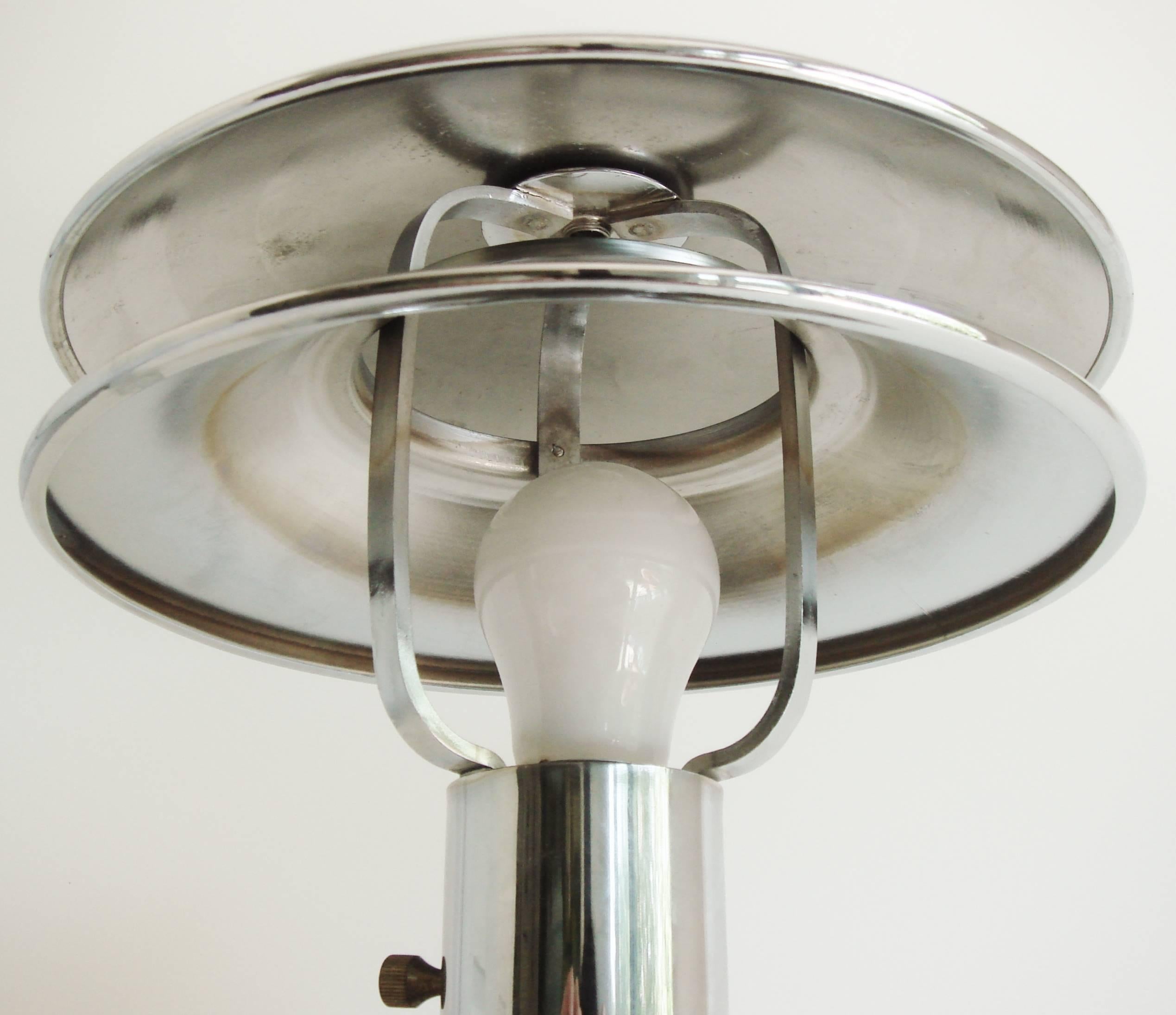 This rare American Art Deco twin shaded chrome table lamp was designed to give discreet illumination to cocktail tables in railway club cars or on ocean liner cocktail bars. It has a low center of gravity, heavy base and an extra hole in the