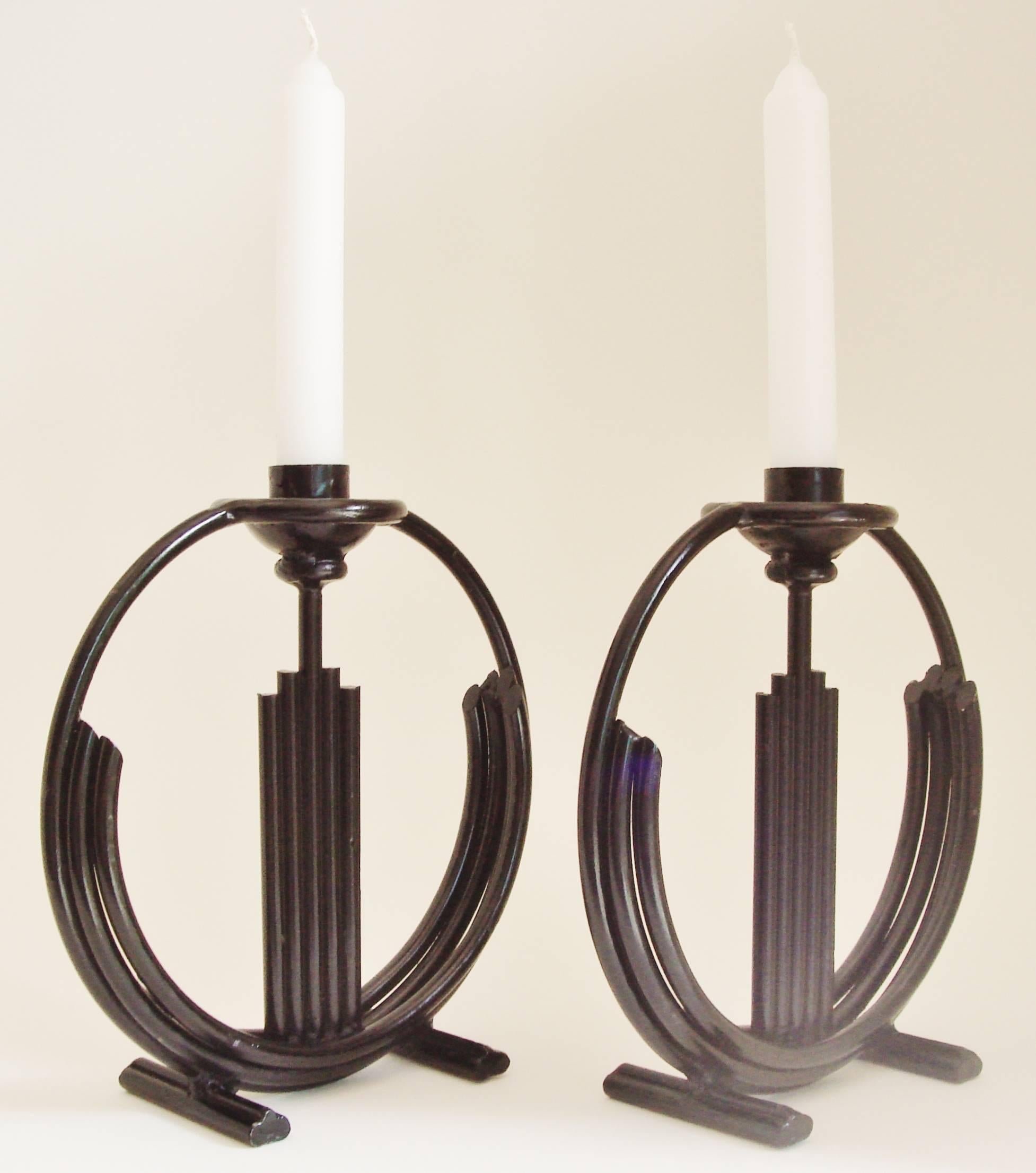 This pair of American Craftsman made candlesticks is a triumph of Art Deco/Machine Age design. This substantial pair is hand constructed from curved and straight tubes of wrought iron combined with sockets and bobeches in cast iron. Both