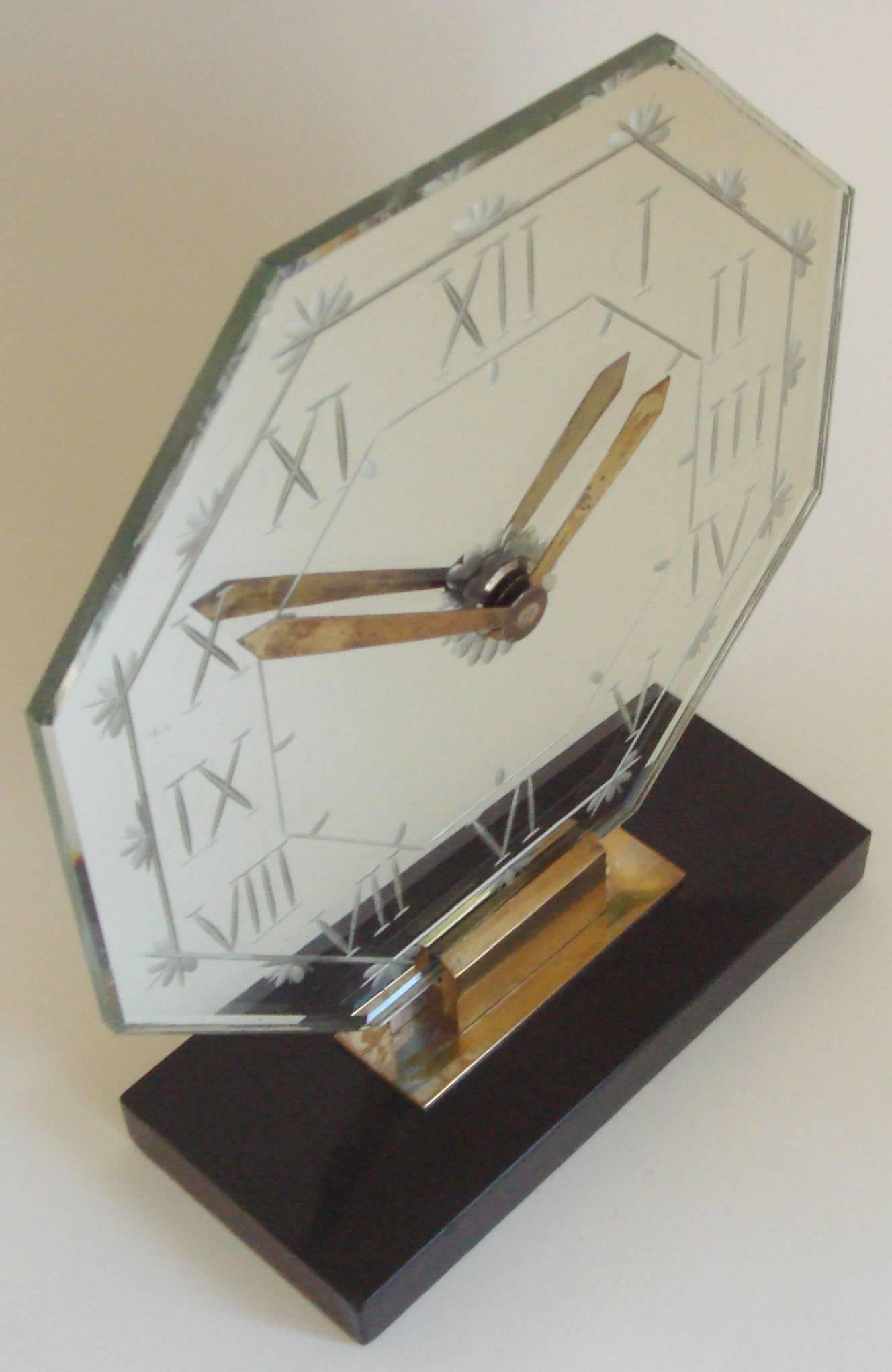 This stunning Art Deco eight-day, mechanical mantel clock is by the famed French clockmaker, Marti. It features an octagonal mirror face with wheel-cut Roman numerals and stylized cornflower designs. It has geometric brass hands emanating from an