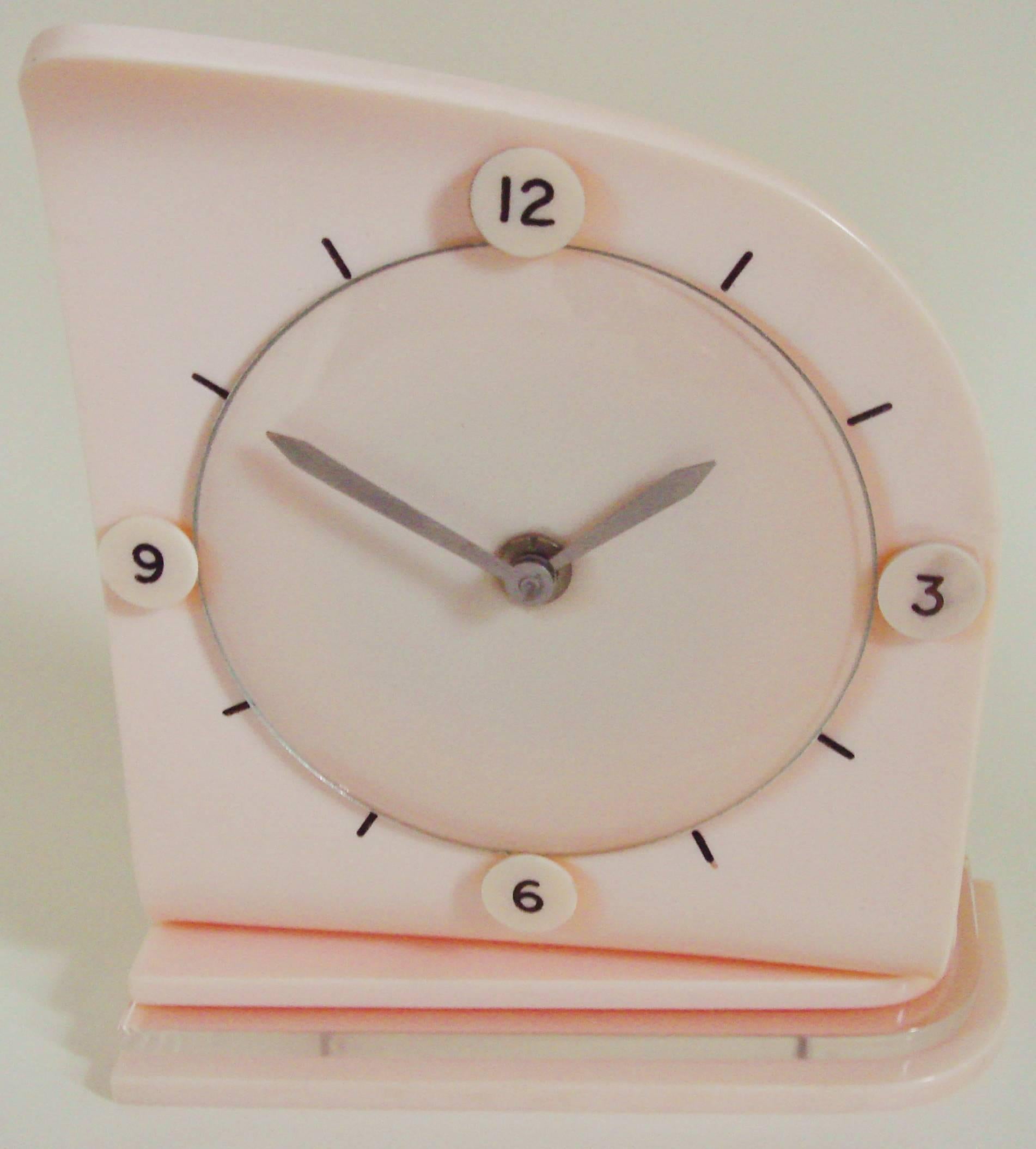 This eccentric and stylishly designed Scottish Art Deco table clock is by the Glen Company. The biomorphic body of the clock is a waveform single sheet of peach Lucite that is mounted to an asymmetrical stepped base. This base is formed from a sheet