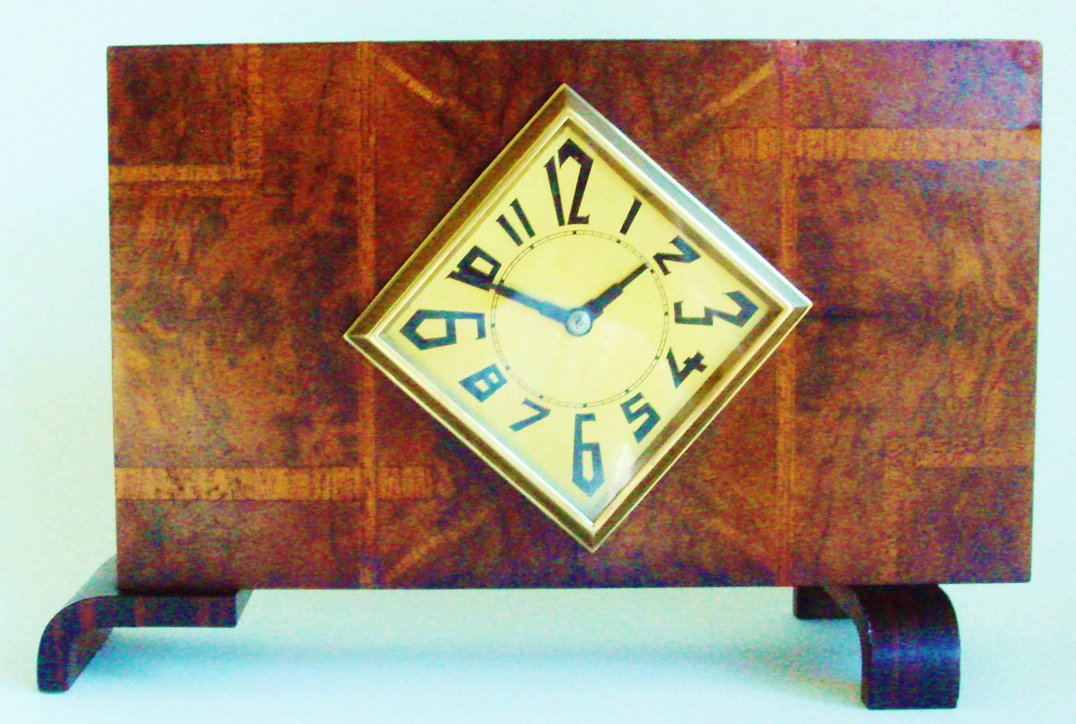This stylish French Art Deco mechanical mantel clock is veneered to the front with a geometric pattern of exotic woods. Veneers of squares and oblongs of burled walnut are separated by strips of figured walnut veneer and laid out in an asymmetrical