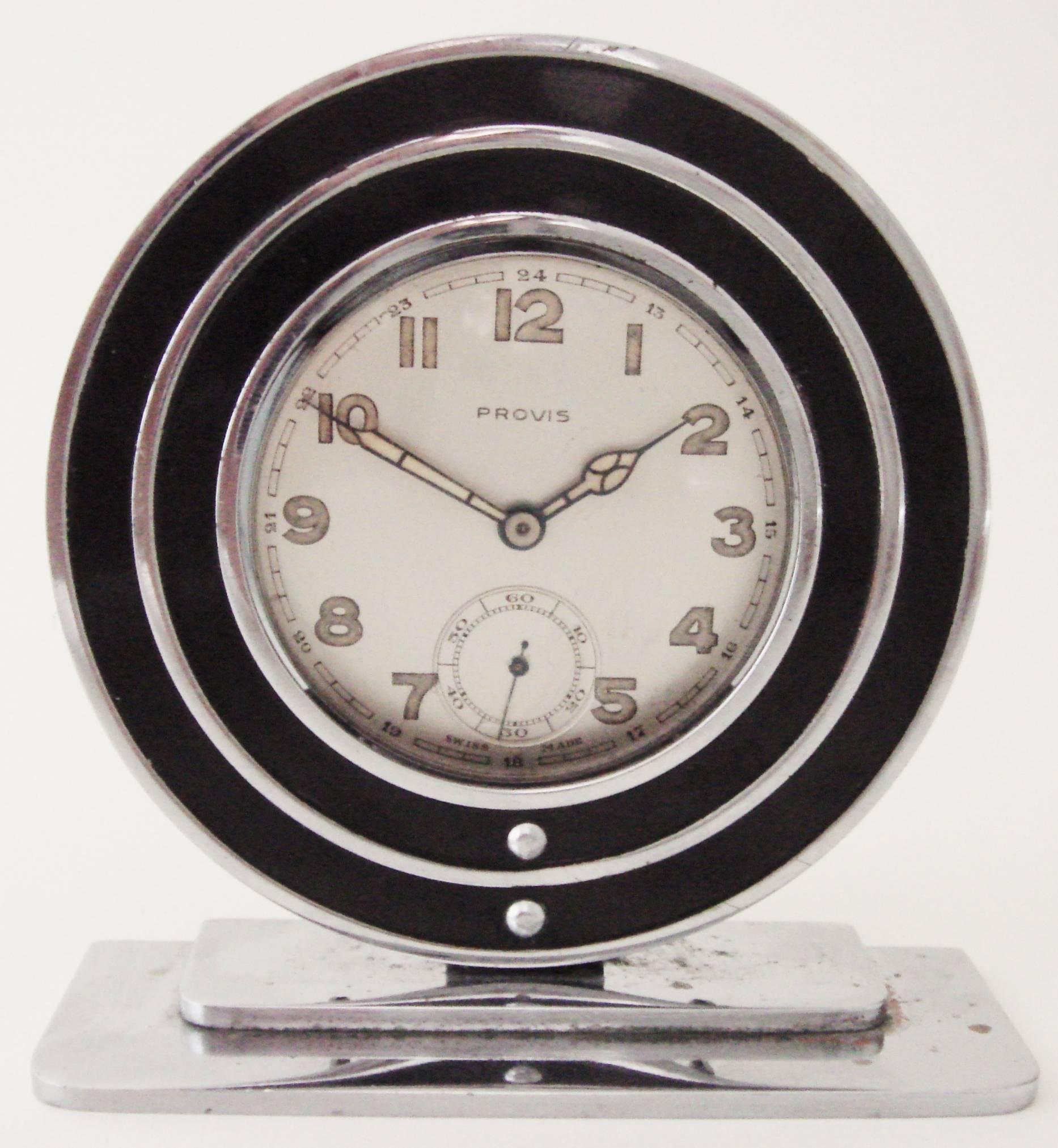 This American Art Deco chrome pocket watch holder features concentric circles of black enamel paint. The stepped base is chrome-plated copper and shows slight plating loss. The back plate watch retainer is in great condition and the spring is