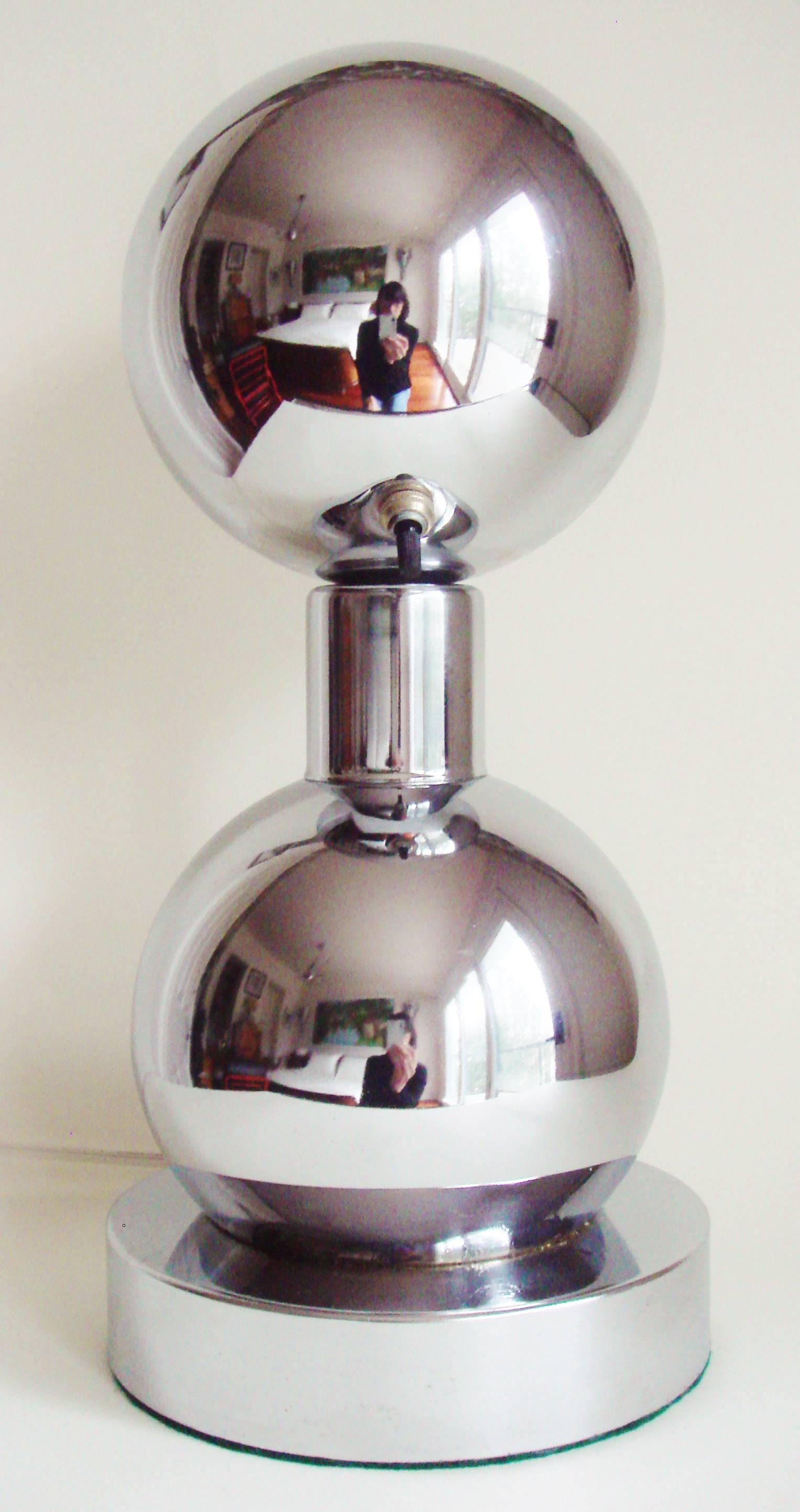 This unusual American space age, double-sphere chrome lamp with its eyeball shade is designed to sit on a table facing the wall in order to throw light on a picture or wall hanging. This style of picture light is hard to find and this particular one