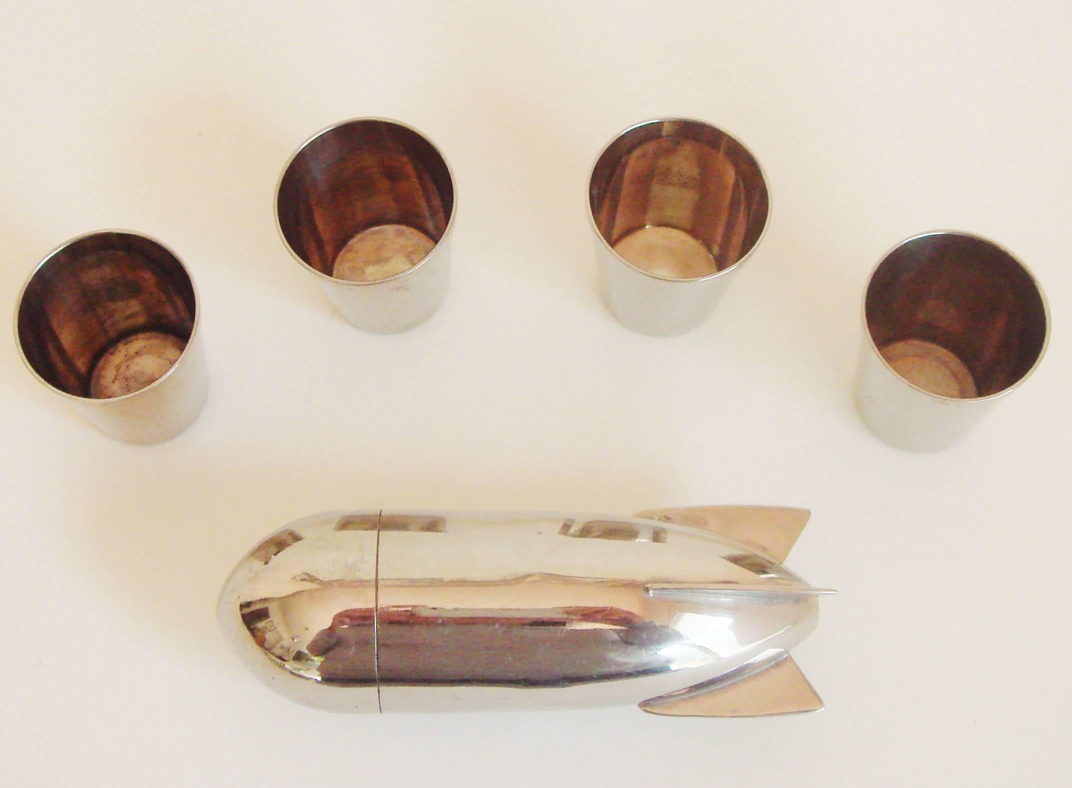 This very rare German Art Deco shot glass set features a chrome container in the form of a Zeppelin with a snap-off nose cone that opens to reveal a set of four nesting chrome shot glasses (each 1.5 in high). Each of the shot glasses is stamped