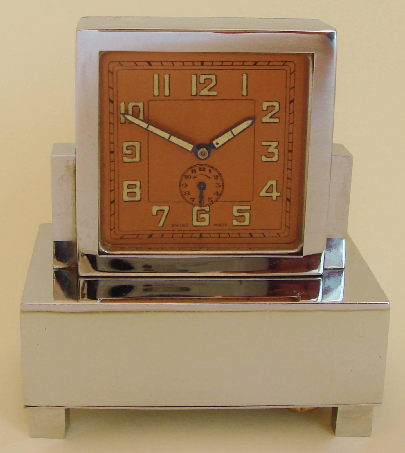 This architecturally designed Art Deco musical alarm clock is by the Liga Watch Company of Solevre, Switzerland. It features a chrome-plated geometric body standing on four cubed feet. The copper face with its Egyptian sans serif numerals and Art
