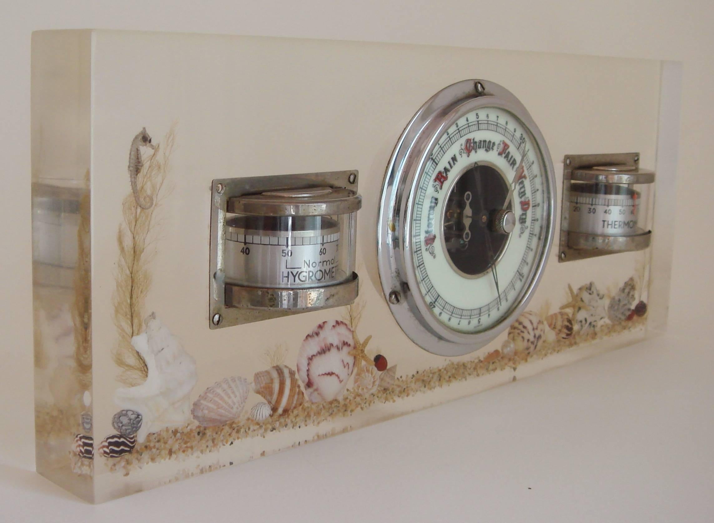 This stylish German Art Deco desktop weather station features a chrome-plated thermometer, hygrometer and barometer set into a block of Lucite. Encapsulated in this block is a miniature seabed of actual sand with assorted shells, seaweed, seahorses