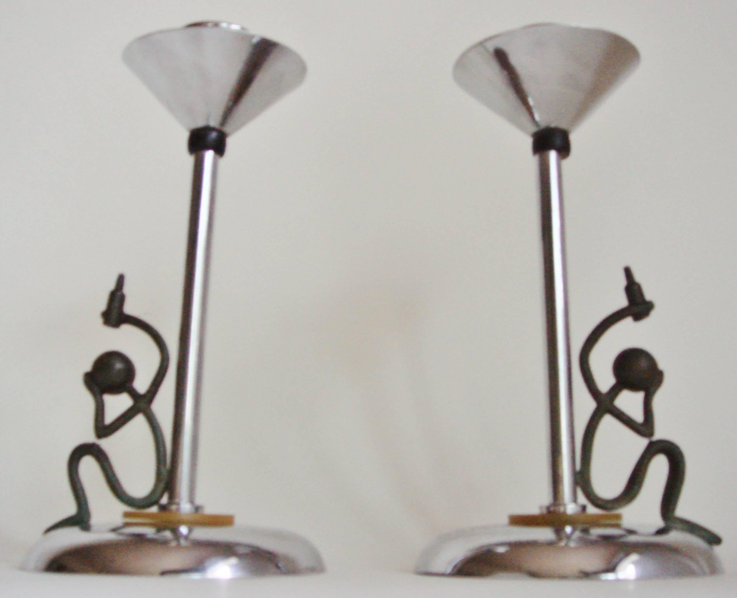 This fun and rare pare of English Art Deco chrome-plated candlesticks are both accented with a green/yellow marbled Bakelite disk at the base and black Bakelite spheres beneath each conical bobeche. Seated on each base and leaning on the chrome