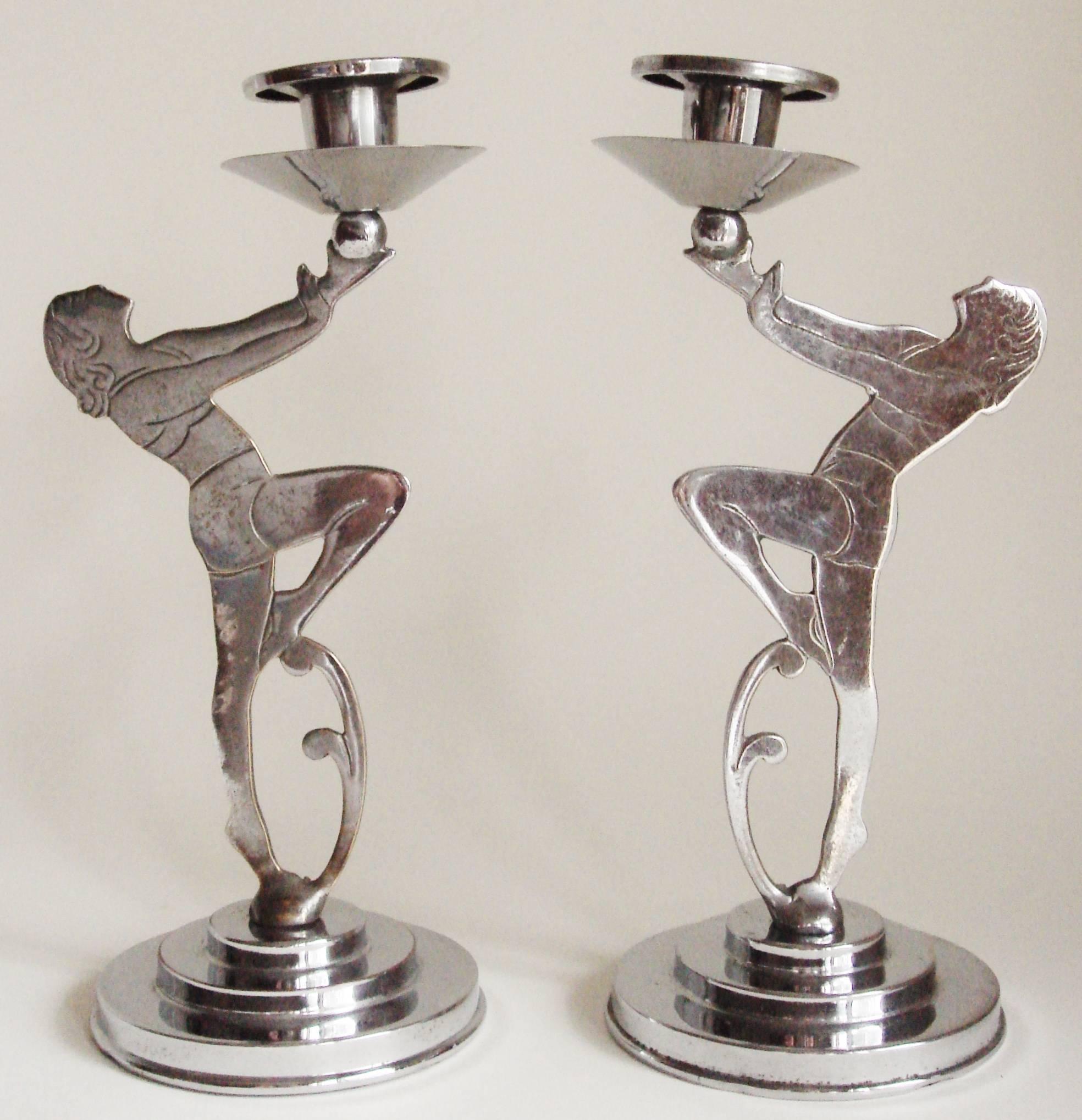 This pair of English Art Deco chrome figural candlesticks feature two athletic young ladies, dressed in period beachware, standing on triple-stepped circular bases and holding aloft the candle holders. Although two dimensional they feature figure
