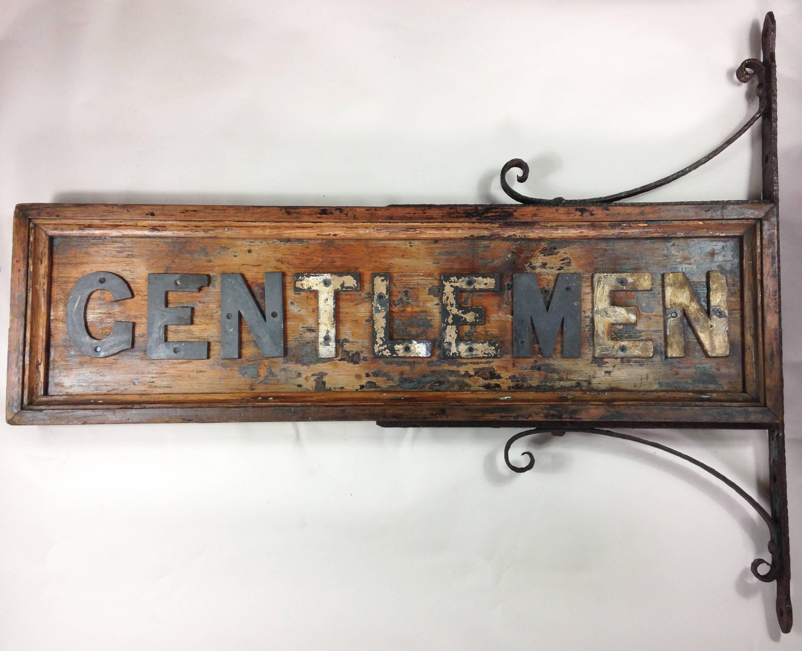 A very decorative 'Gentlemen' wall-mounted sign which originated from an old British railway station. 

The wooden sign with applied lead letters has been stripped on one side and has evidence of old paint to some of the letters, however this just