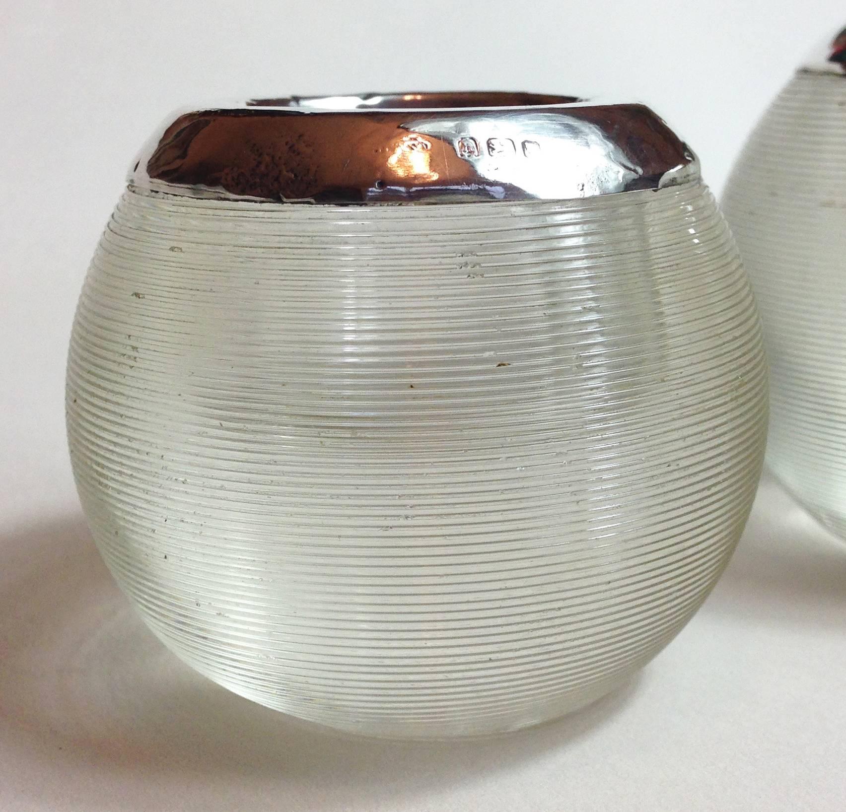A pair of Edwardian threaded glass match strikers with hallmarked Sterling silver collars.

The smaller of the two is approximately 5 cm tall and 6 cm across. The glass is in good condition. The silver collar shows wear commensurate with age. The