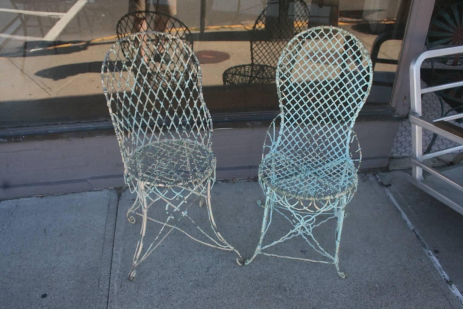 Great pair of Victorian wire chairs. These chairs have beautiful turquoise and pale yellow paint on them. It may not be original but it's very old paint. These chairs are not an exact pair but they are pretty close. They have the fence look seats