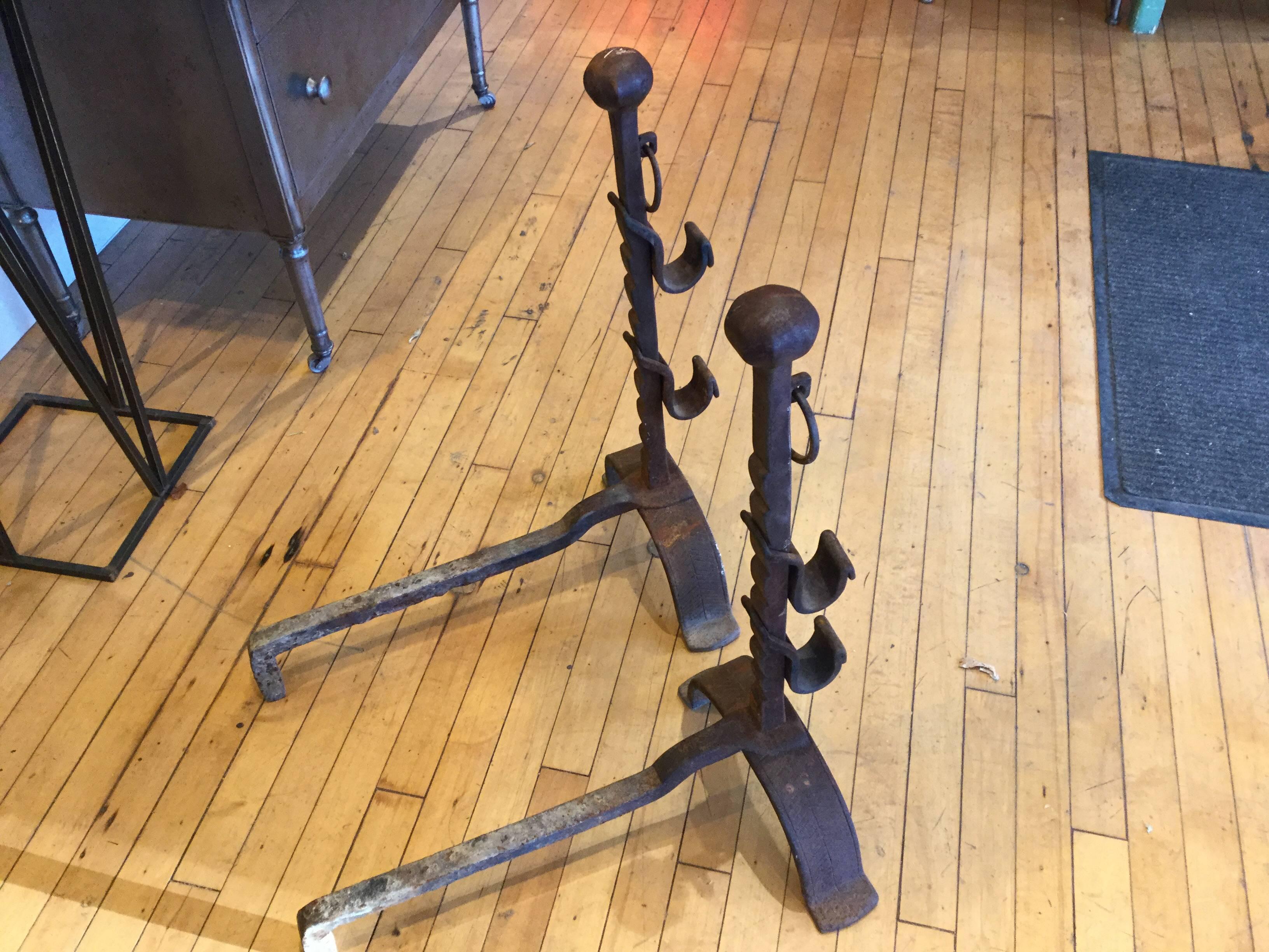 Large pair of 18th century hand-forged fireplace tools or log holders. Herringbone design inscribed in the feet and brackets. You can almost see the iron being molded by hand. These were used for cooking in a fireplace and have several levels the
