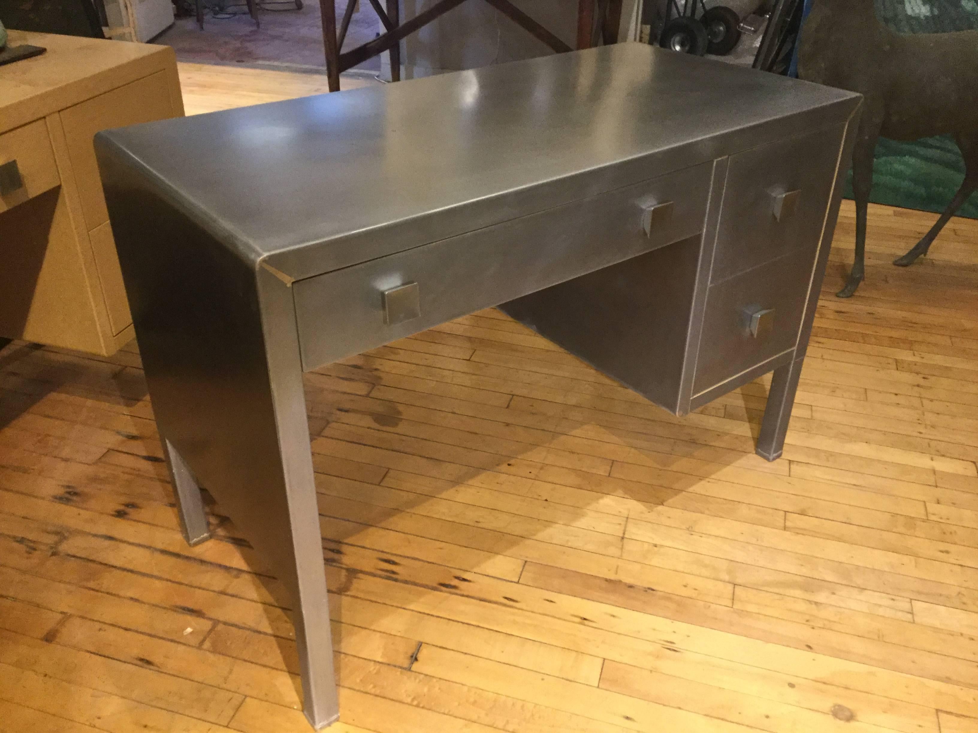 Mid-Century Modern steel desk. Originally these desks by Simmons and designed by Bel Geddes were painted in a blond faux wood finish, but stripped they take on an elegant Industrial look. Great design. Drawers are all perfectly flush with surface