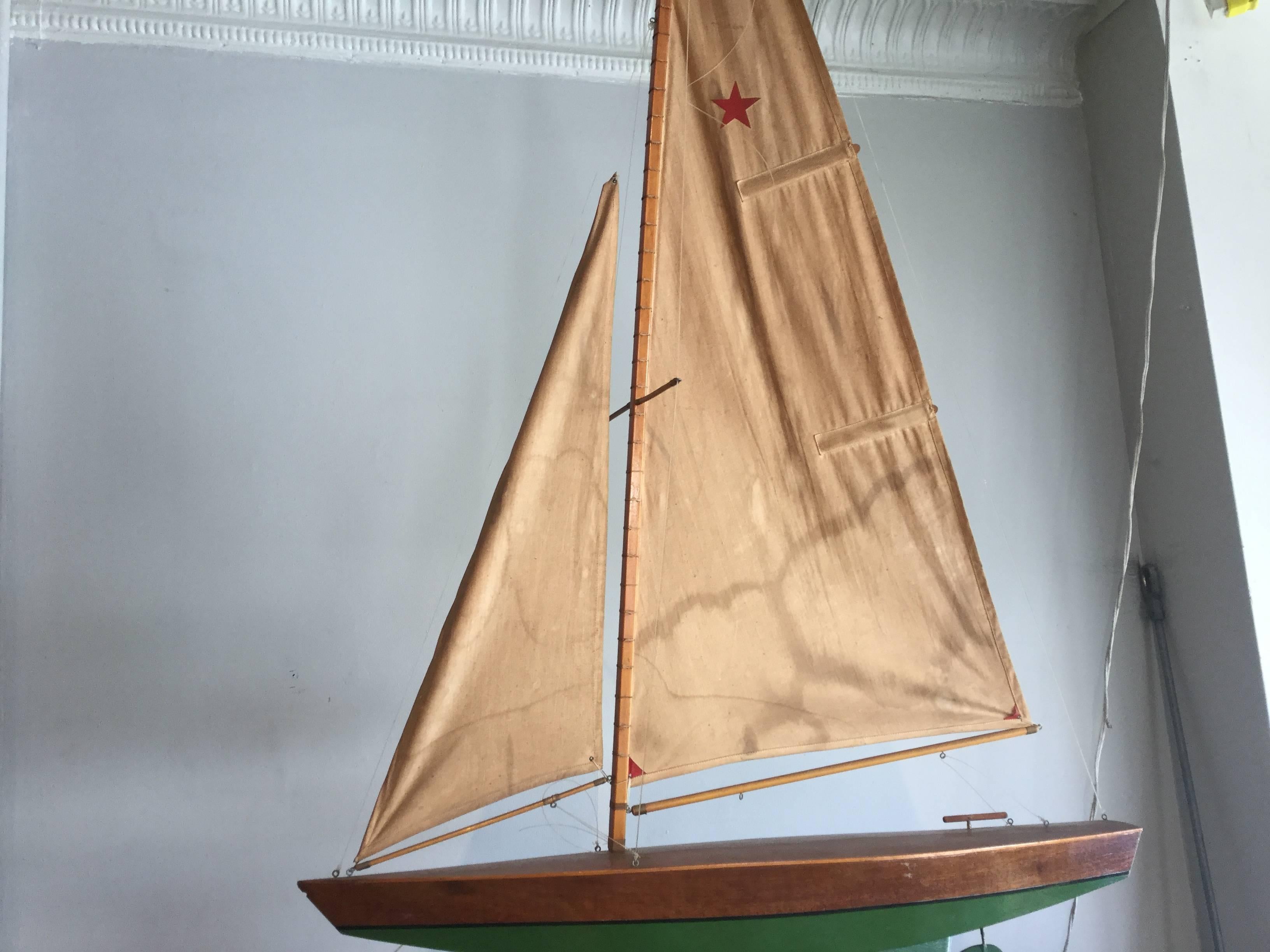 Tall pond boat with green hull and original weathered sail. I love the red star on the sail. The boat has seen use over the years and has a great overall antique patina. Great color and great faded sail.