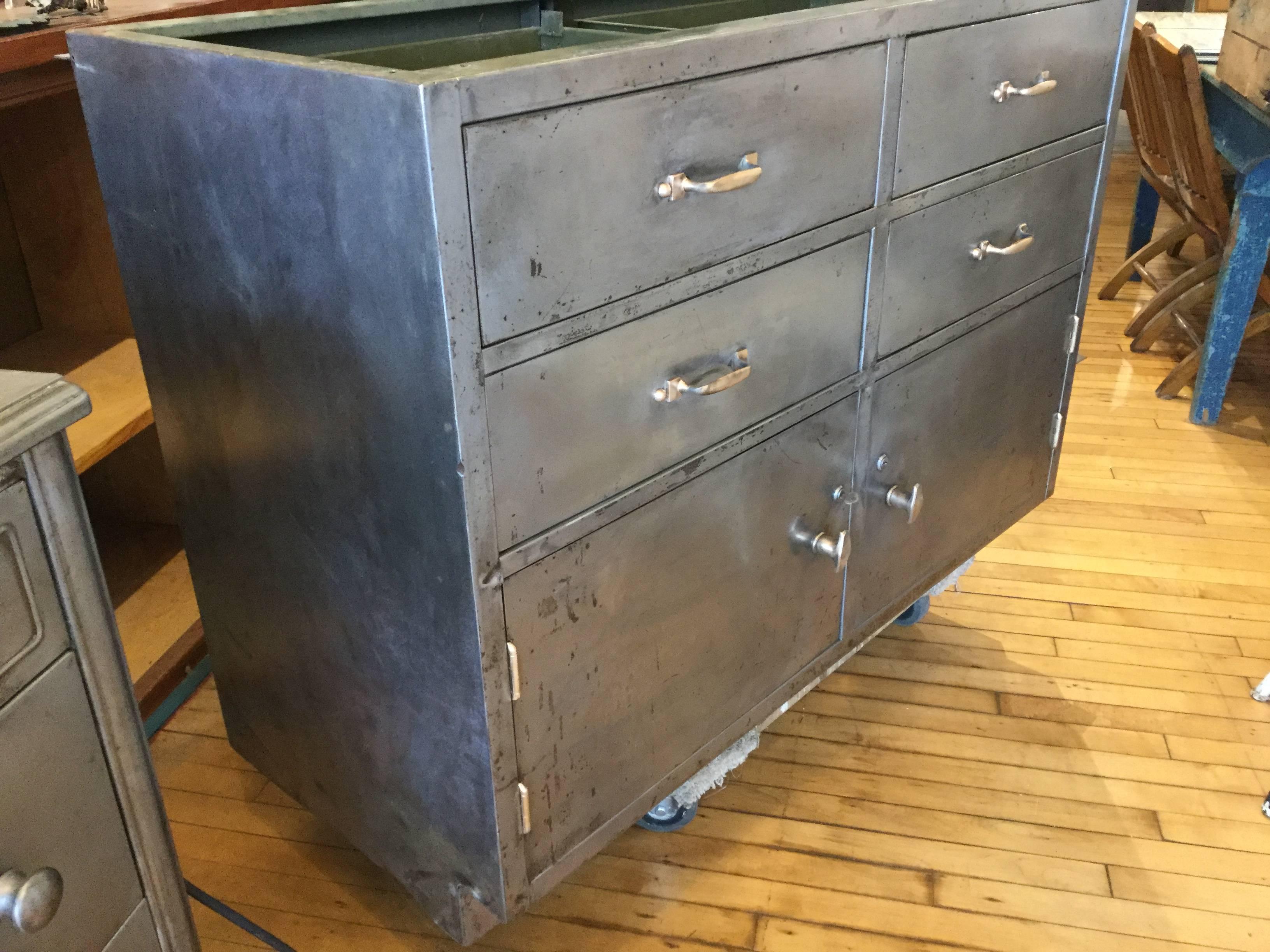 1920s Industrial steel cabinet with brass handles. Gorgeous patina on the old steel. This piece needs a top. Marble butcher block. Soapstone lots of things could be beautiful on top of this piece. The piece is modular and fits on the end of the
