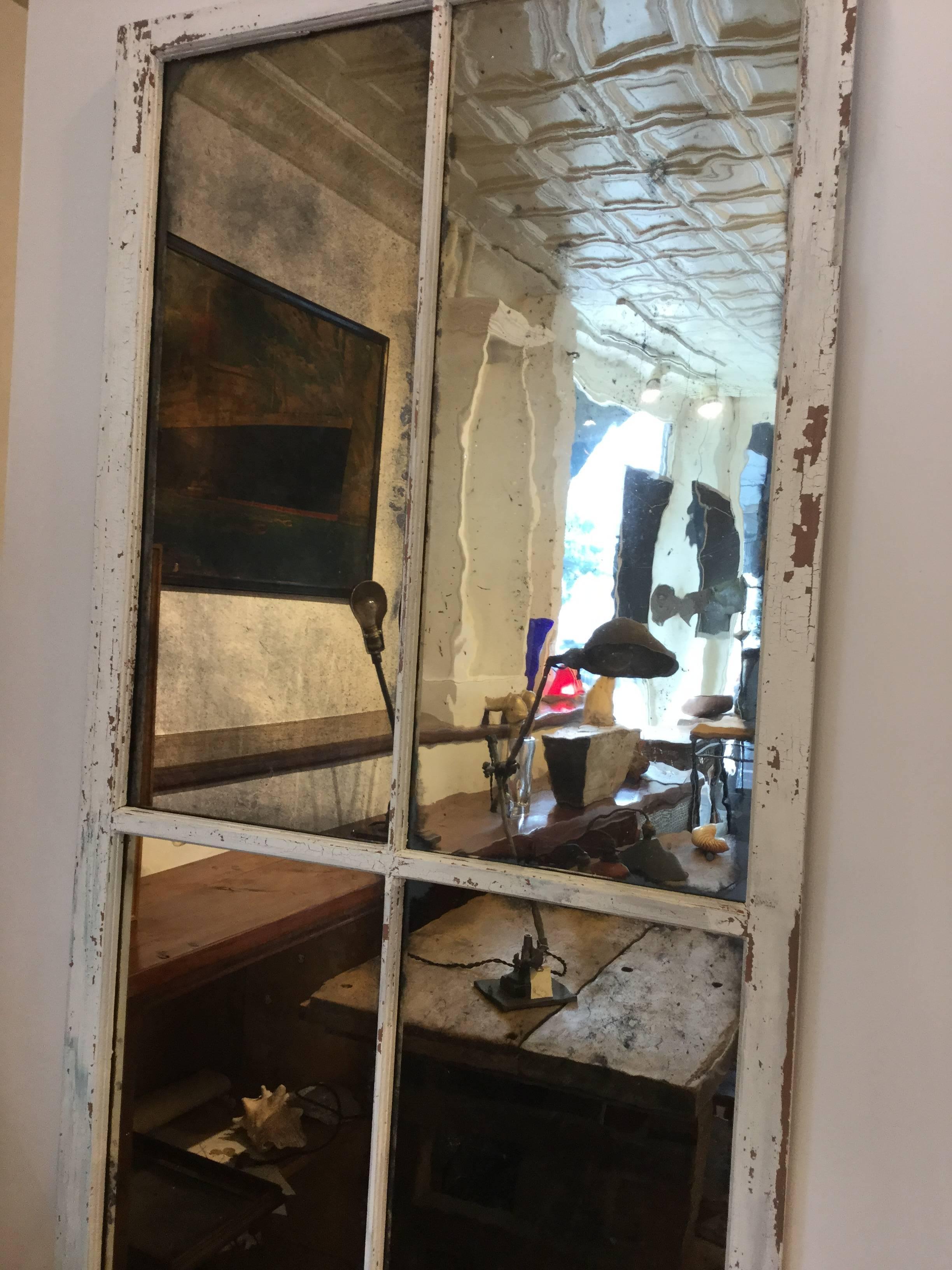 Old four-pane window with original wavy glass that silver has been applied to make an interesting architectural mirror.