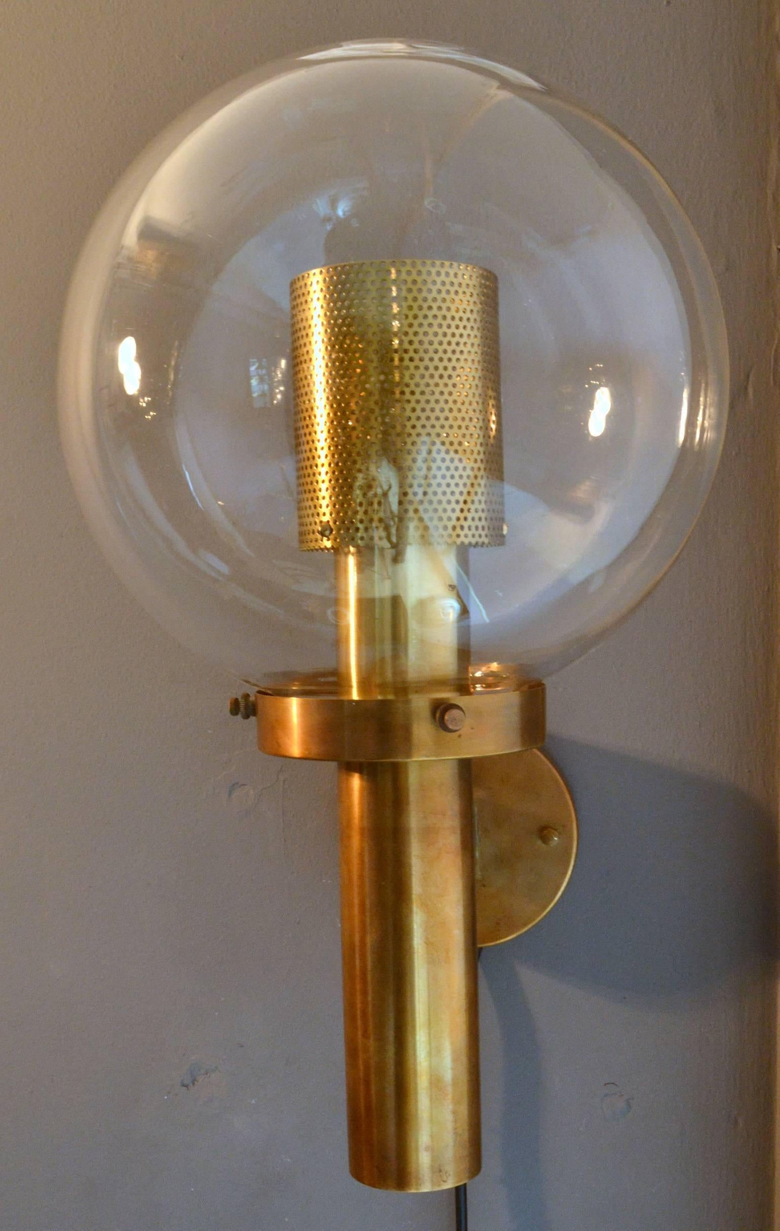 Scandinavian brass wall lights with clear glass globes by Hans-Agne Jakobsson for Markaryd AB, Sweden, 1960s.
The two sconces each featuring a clear glass globe with inside a brass body with perforated brass light diffuser that creates subtle