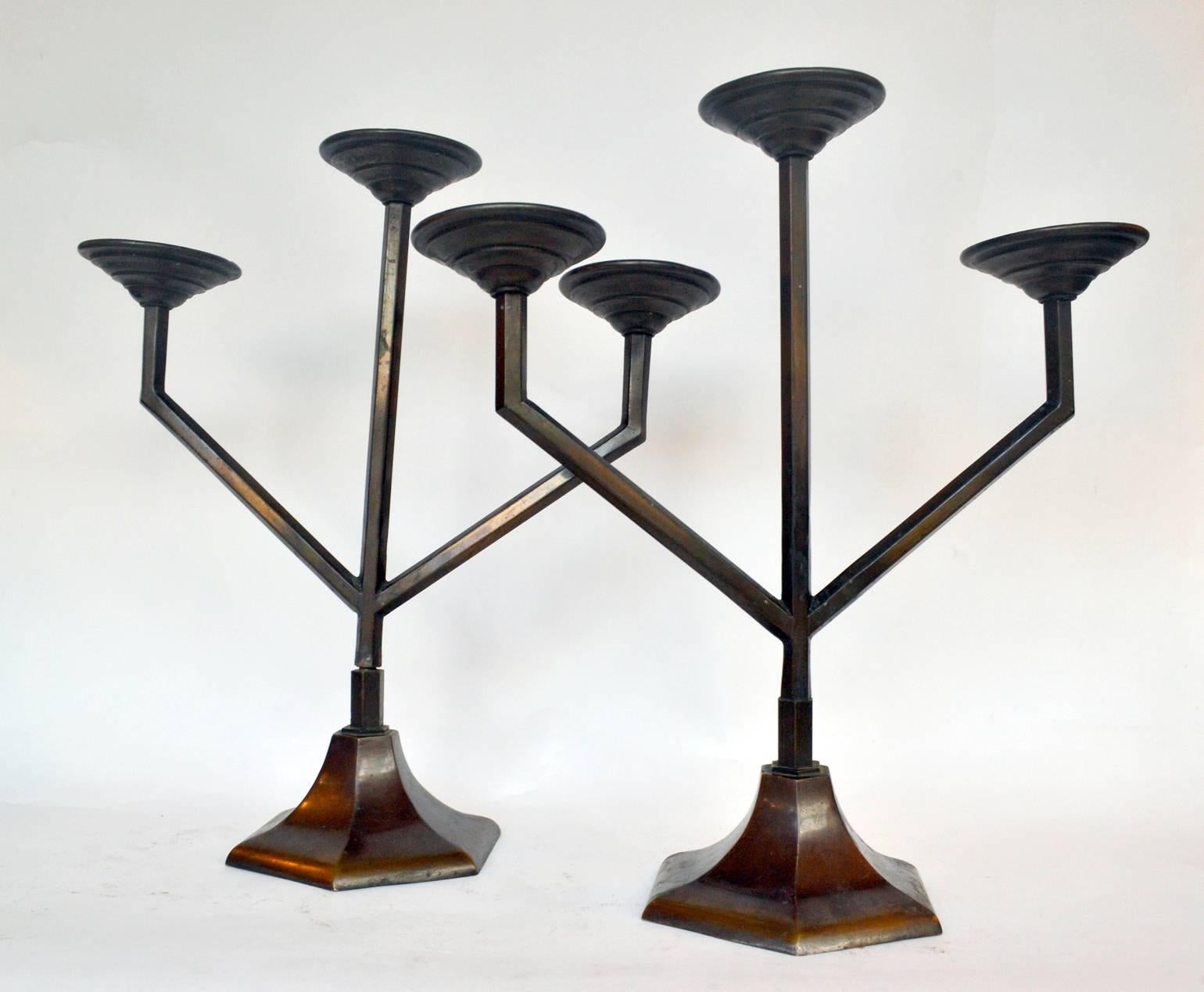 Two Art Deco handcrafted copper candelabras each with three arms and designed with geometric lines. The copper has a dark patina.