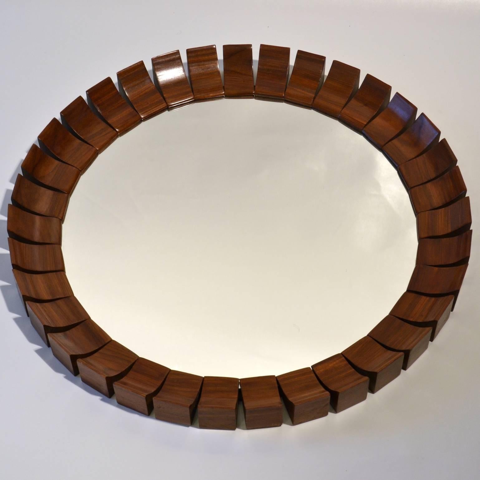 Danish sunburst wall mirror edged in an array of palisander wooden pieces. This unique frame is adorned with individual carved solid wooden elements, each ray representing the luminous power of the sun.
     