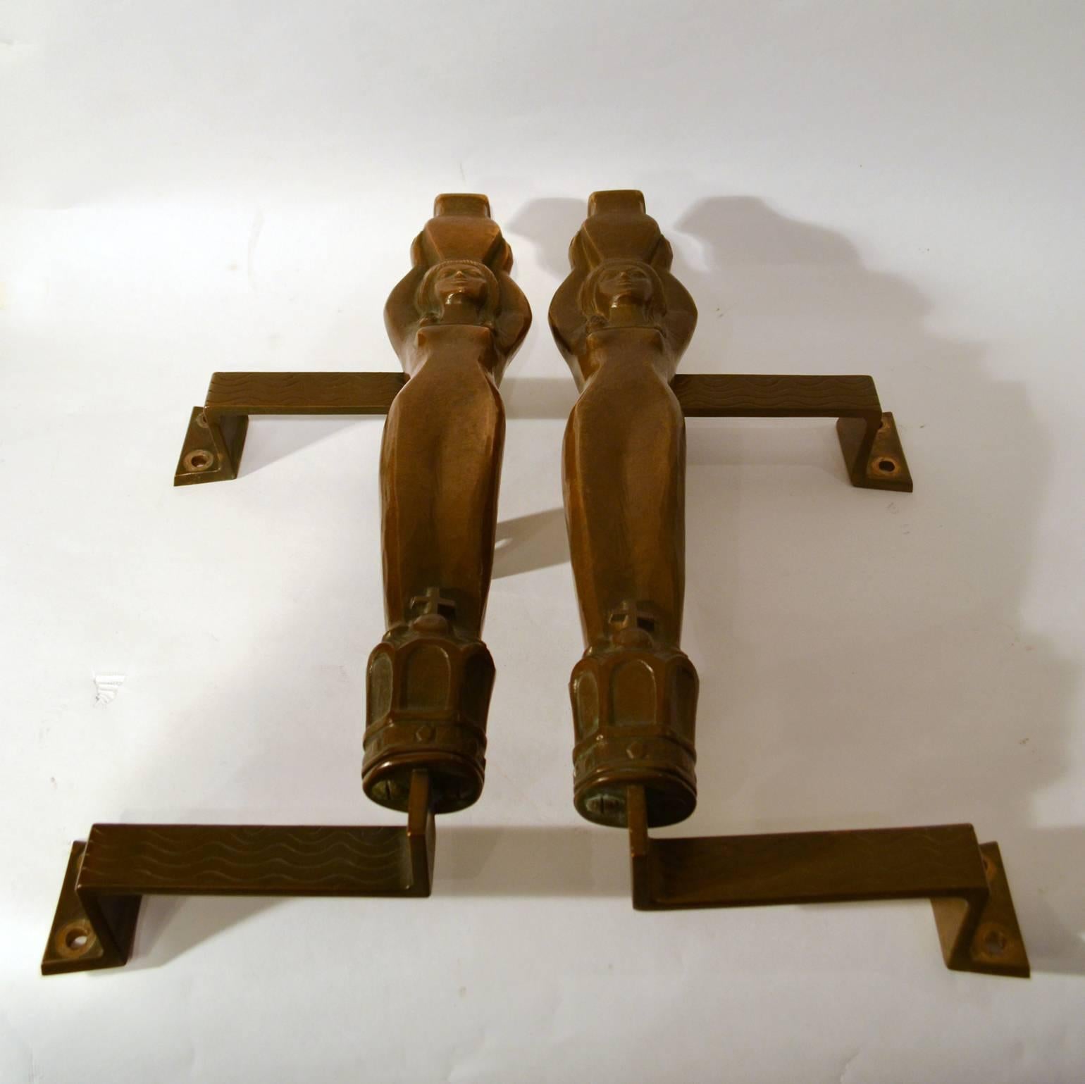 Original pair of door handles in the shape of two water nymphs, from spa in the Alps.
The nymphs carry water jugs on their heads and stand on crowns. These large patinated bronze push & pull door handles are decorated with waves where they meet the