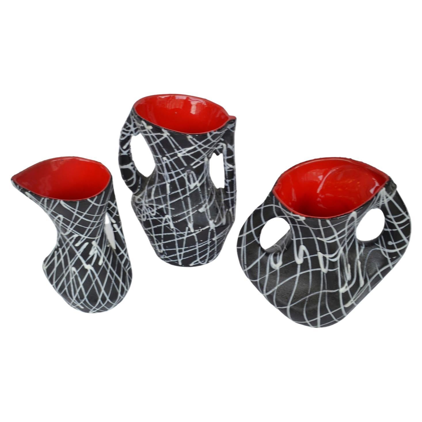 Three freeform vases decorated with a expressive patterns like the action paintings of Jackson Pollock in white on a black glaze background and vibrant red glaze inside . Made in France 1950s and signed Vallauris.