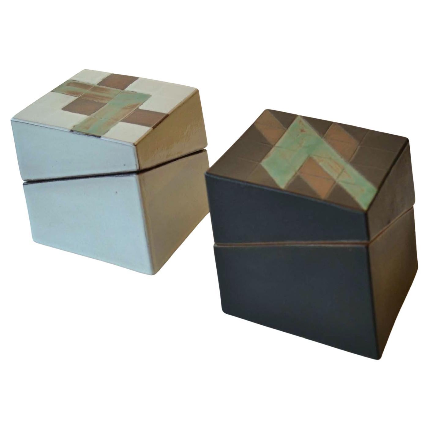 Two leaning square Studio Pottery boxes glazed in black and white with oxide green added in the geometric pattern on top. Sculptural decorative and functional boxes, signed PS are late 20th century. The lids fit precisely on the bases of the