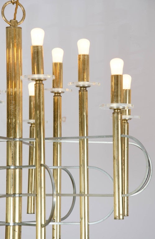 Sculptural Space Age chandelier with clean lines in brass and nickel with clear glass disks displaying 12 lights by Gaetano Sciolari, Italy.

The maximum drop is 100 cm and the chandelier height is 54 cm.
Possible light bulbs, candle, golf or