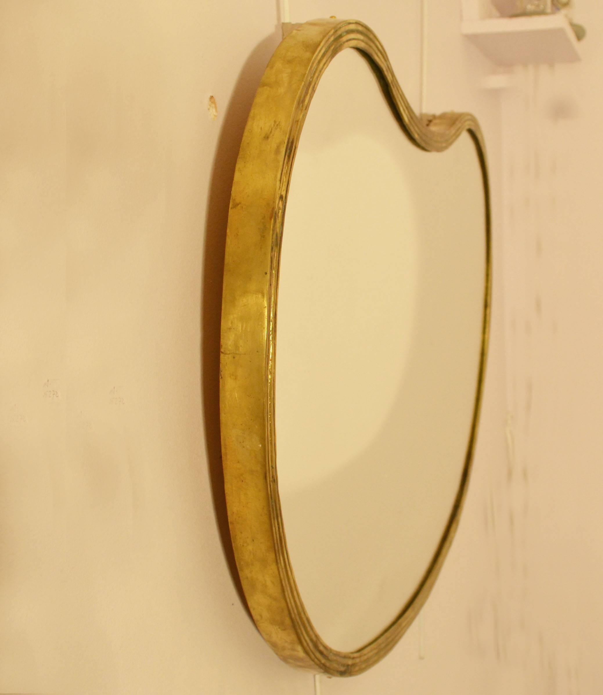 Free-form organic mirror with a patinated cast edge. The shape is emphasized by the channel of lines.