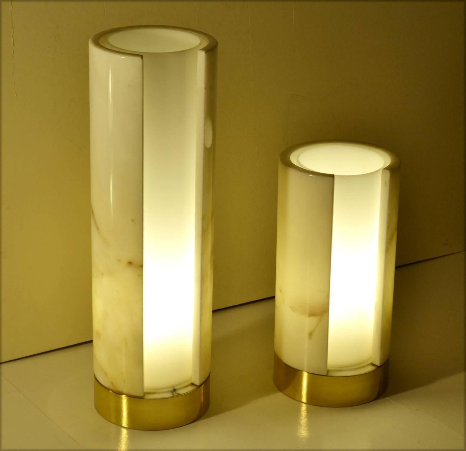 These minimal Carrara marble lamps have been carved to a thin wall which lets the light through and shows its veins. Inside a cylinder of plexiglas diffuses the light.
The two lamps have different heights 42 and 28 cm.
The diameter is the same for