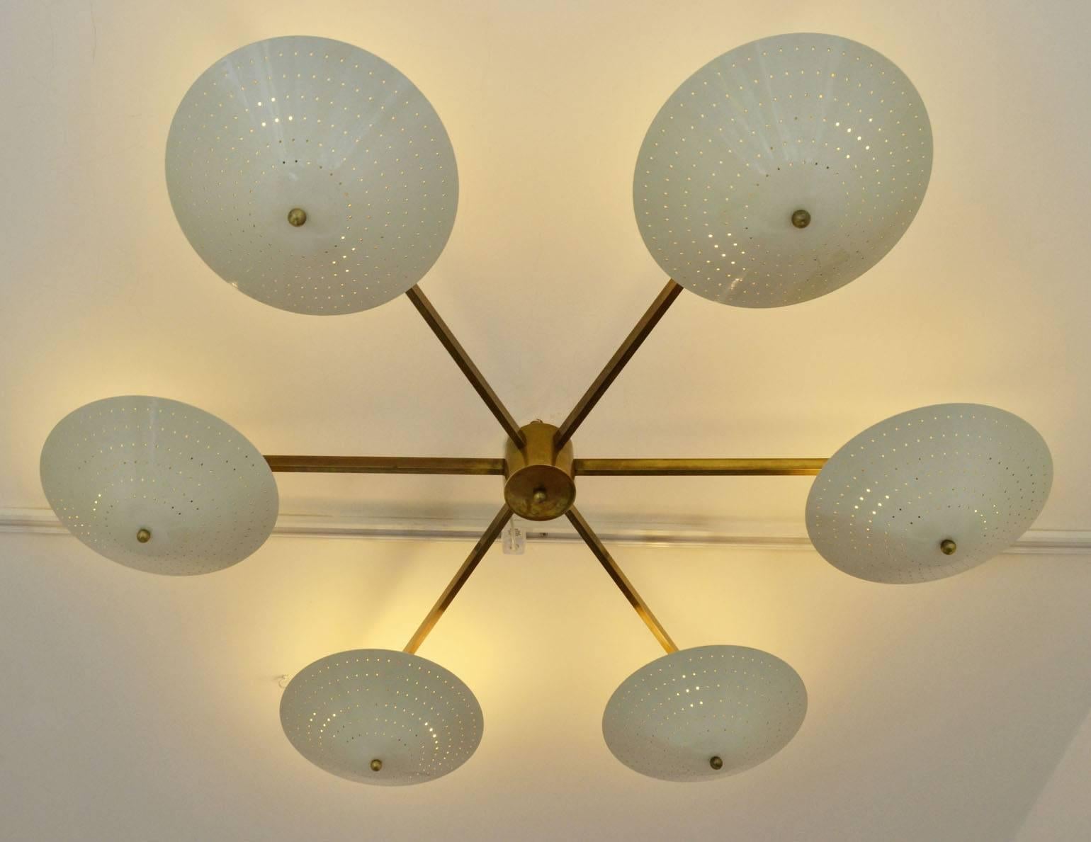 Elegant Up-lighter chandelier with six cream perforated concentric metal shades radiating from a six arms brass tubular frame and connected by a brass central cylinder cup.
Excellent statement as a centerpiece for a living room. 
Optional the