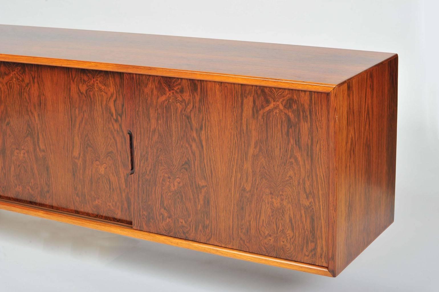 Floating sideboard with simple lines in beautiful patterned hardwood veneer.
Four sliding doors open in symmetry sideways revealing each an adjustable shelve, great for objects on display. Great storage unit.
The sideboard comes with strong wall