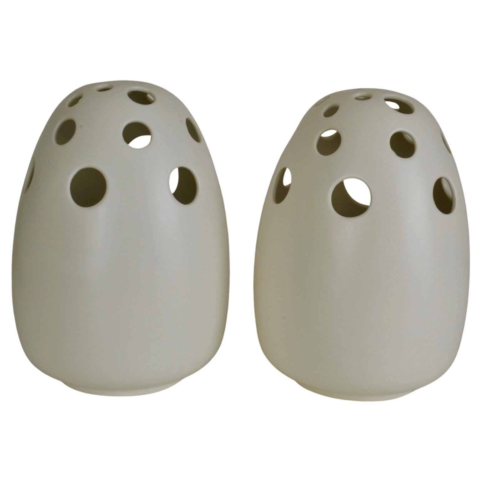 Large decorative cream ceramic vases are sculpted into an egg form. The proportion and scale of the vase lends its self to the simplest or most spectacular flower display.
The perforated holes cover at the the top of the vessels alternating into a