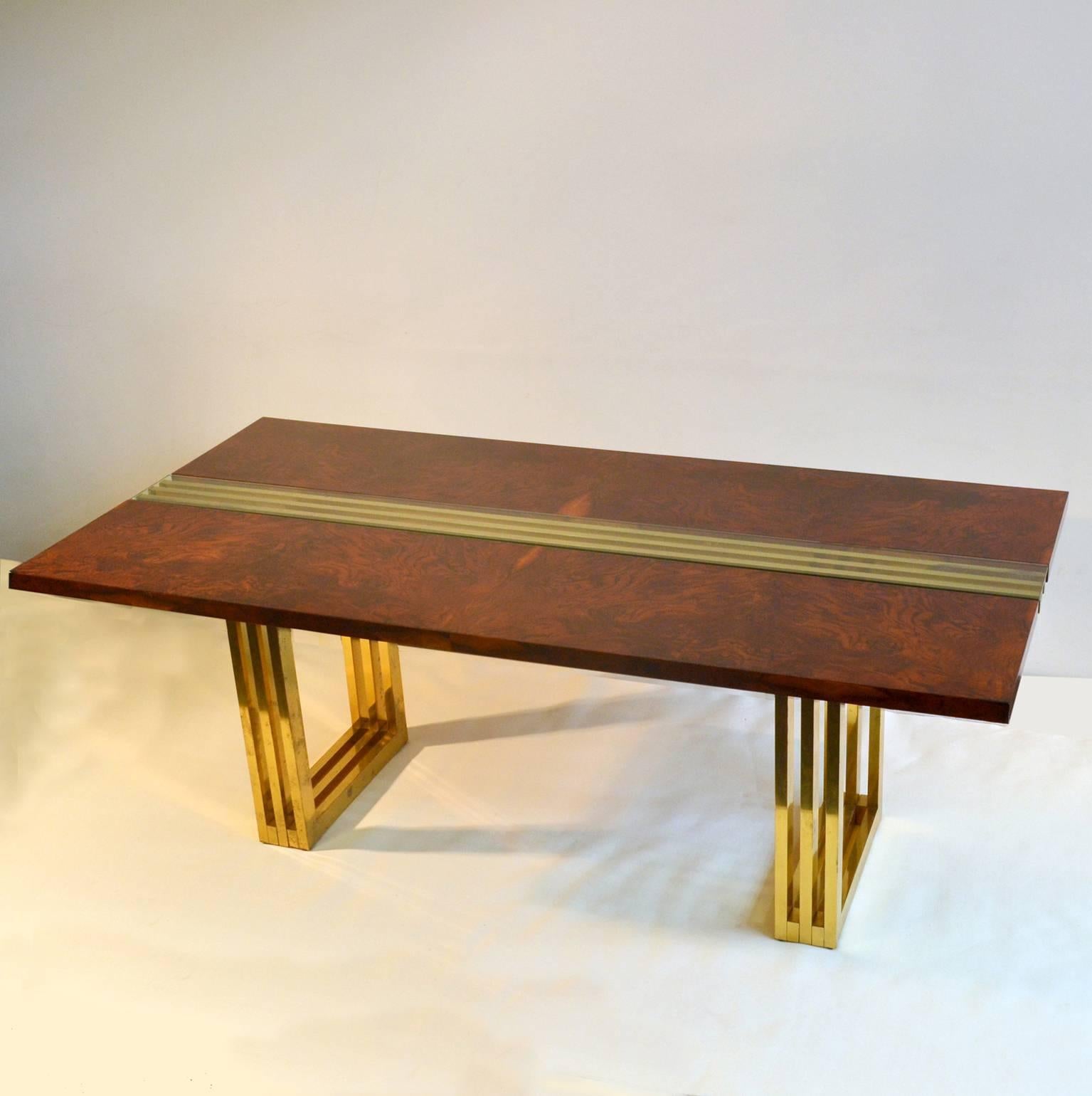 The top of the two meter long dining table is made of two leaves side by side in burl walnut with a middle panel of glass which enable us to see the construction of brass. Geometric rhythm of square brass tubes form the construction of this table