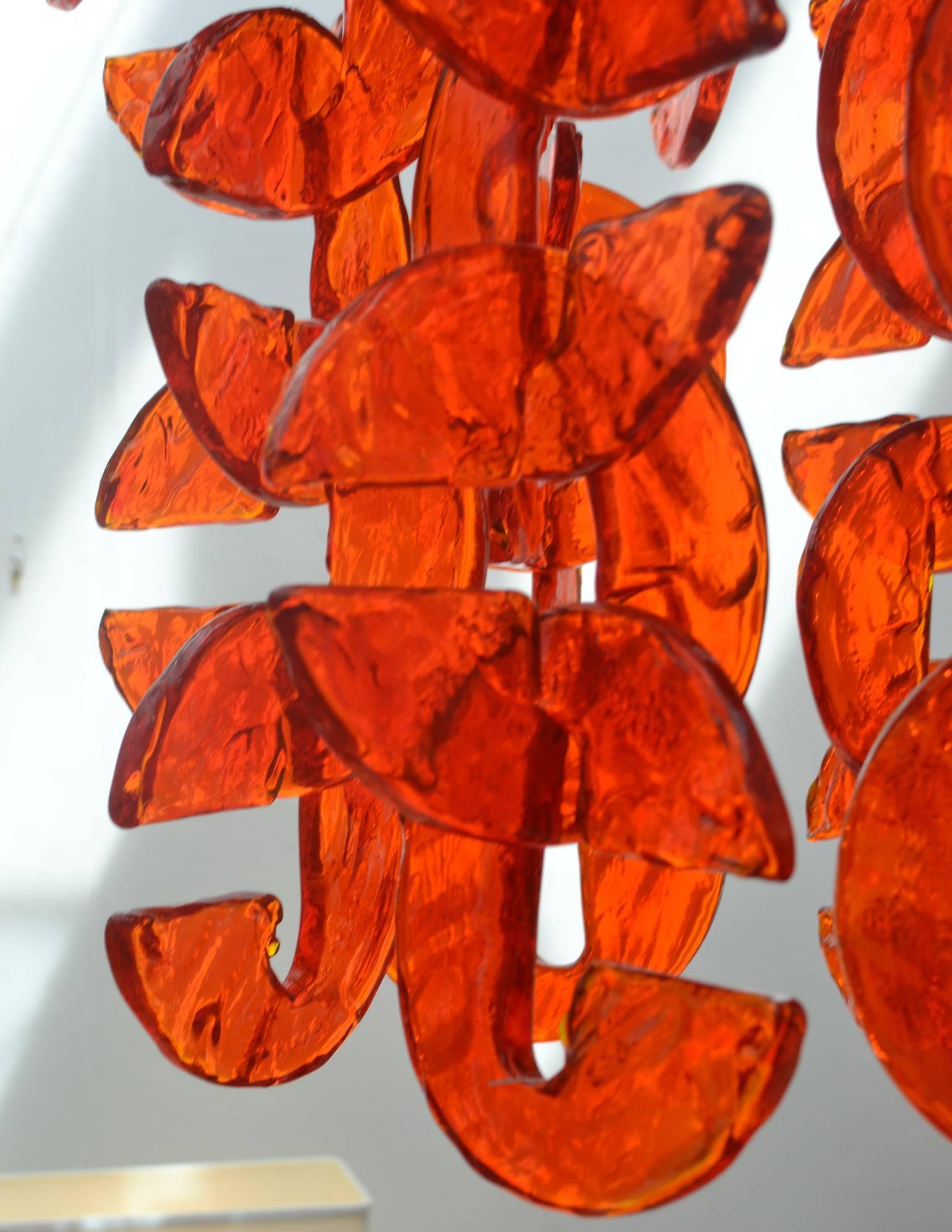 Bright orange colored 1960's chandelier with over a hundred glass pieces shaped in abstract letter 'C' hooks into each other forming a cascade of strands that can be adjusted into different design.

The height of the glass chandelier is 85 cm max.