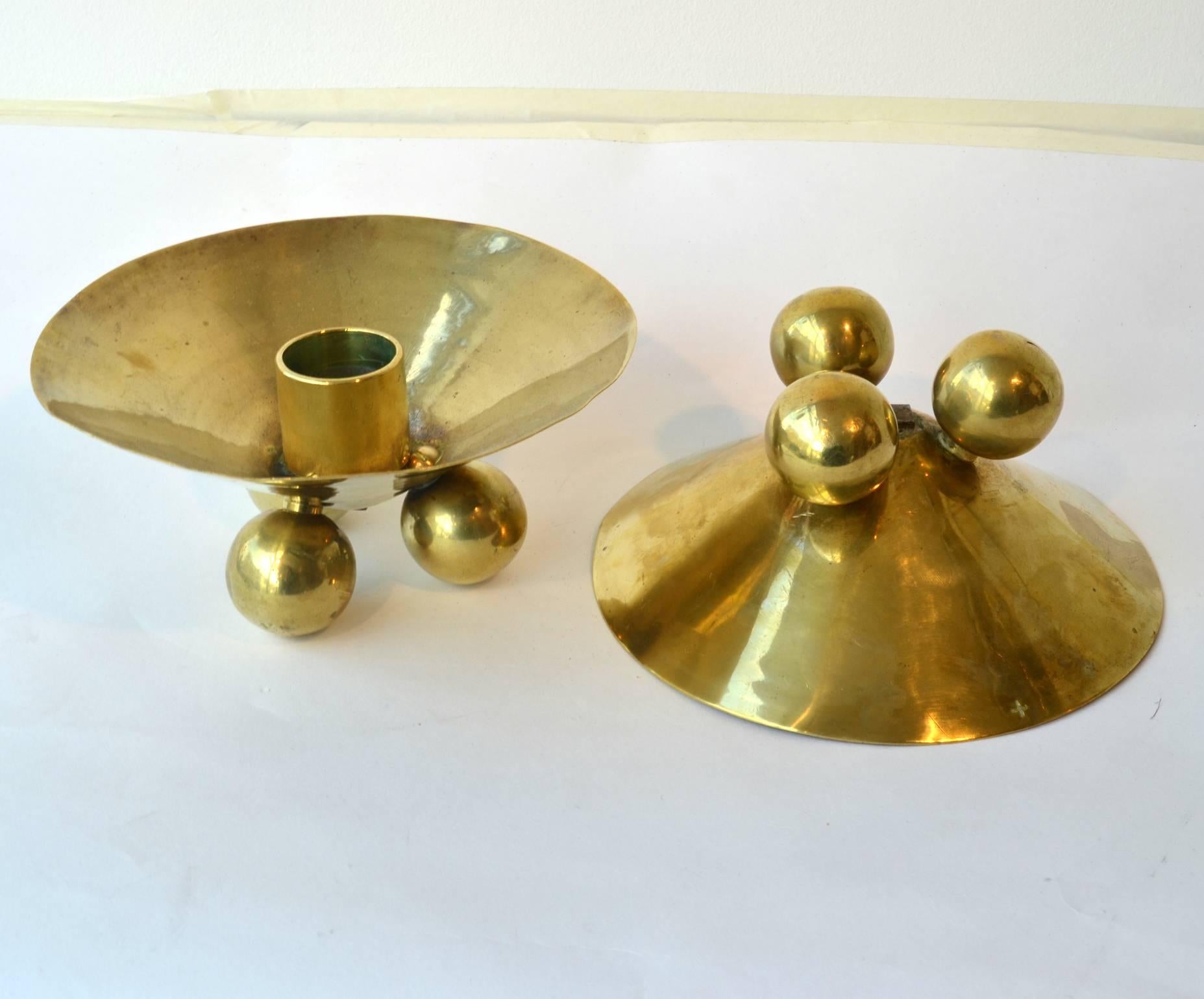 Sculptural pair of brass candlesticks handcrafted on three ball shaped legs.