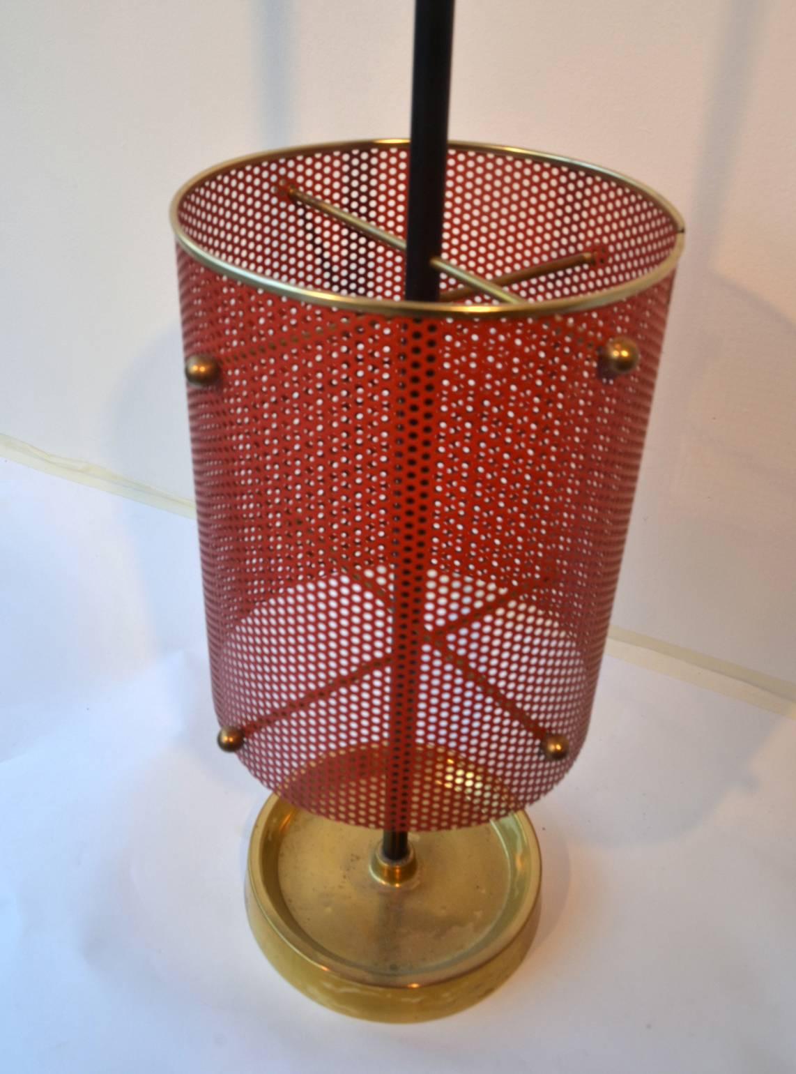 Brass foot holds a red perforated umbrella Stand. Compact and elegant design typical of the 1950s, France.
 