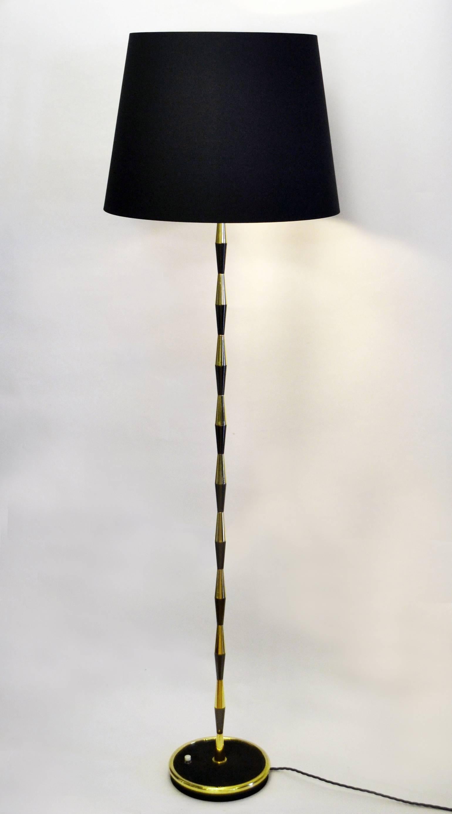 Brass floor lamp in the style of Maison Lunel / Arlus with a stem in alternate brass and black beads and black base with a brass rim has a new lampshade.